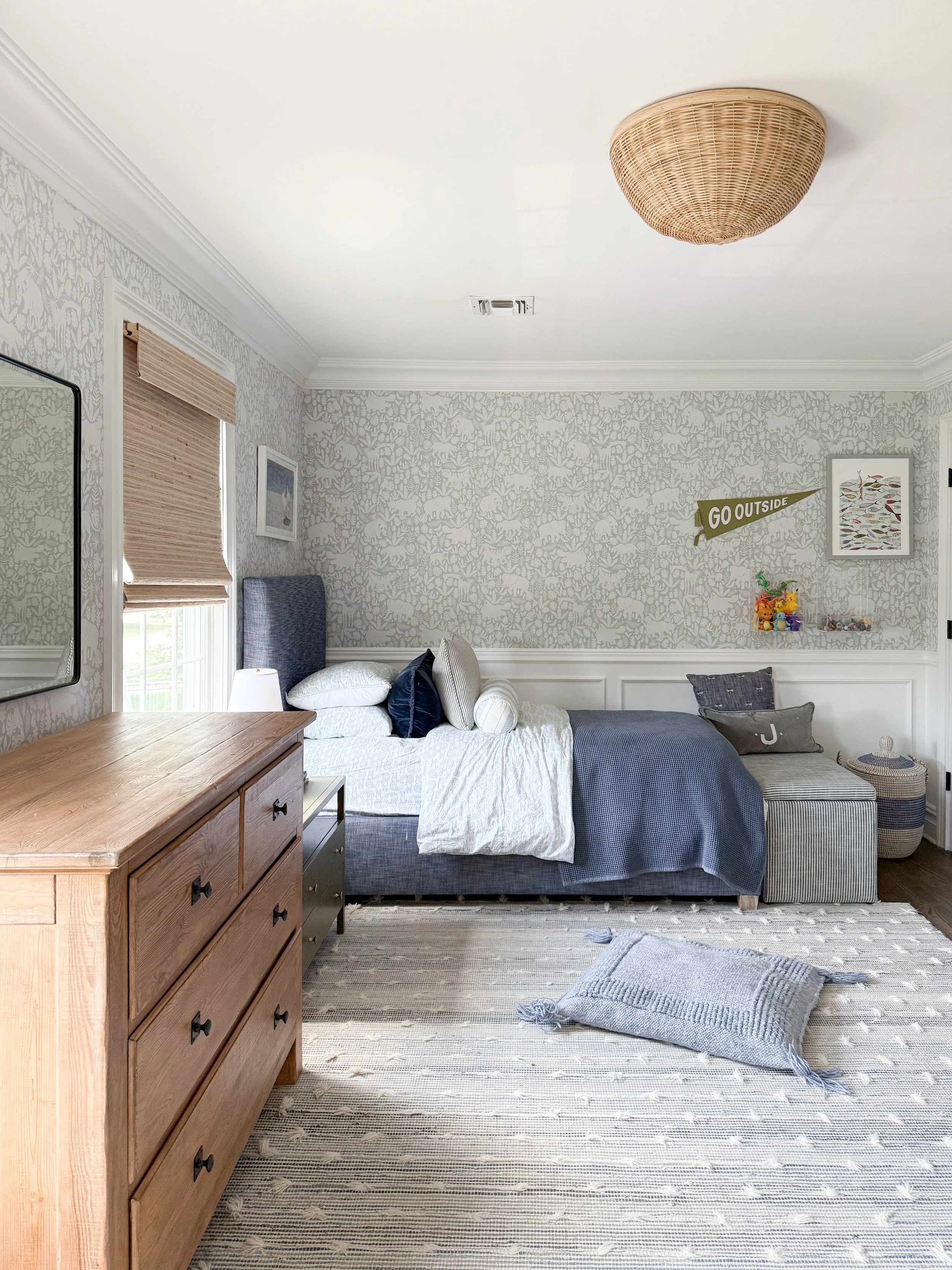 Boy's bedroom with blue accents, a neutral patterned area rug, and classic coastal inspired décor.