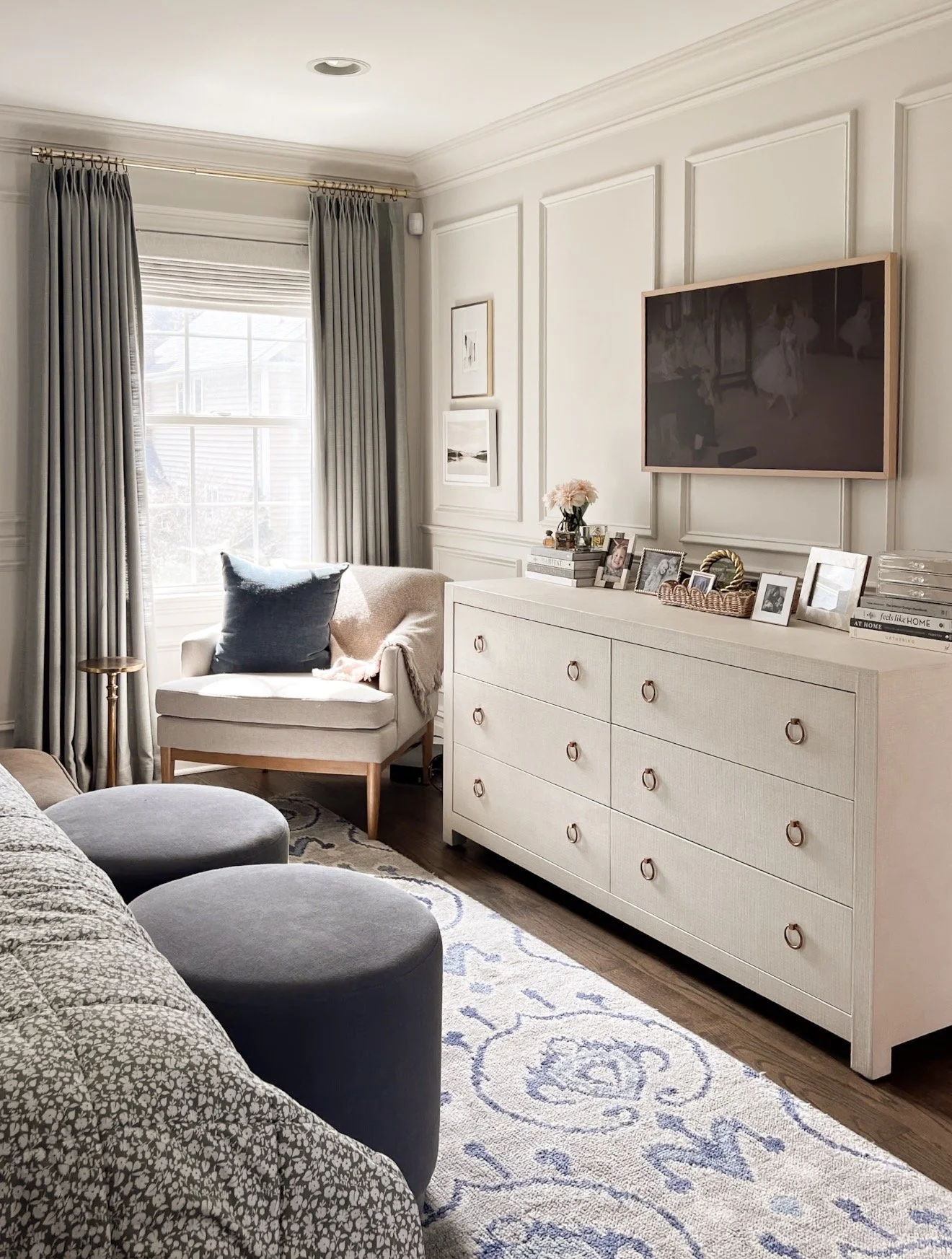 Neutral primary bedroom with upholstered bed, textured bedding, wood furniture, and soft warm white paint color palette.