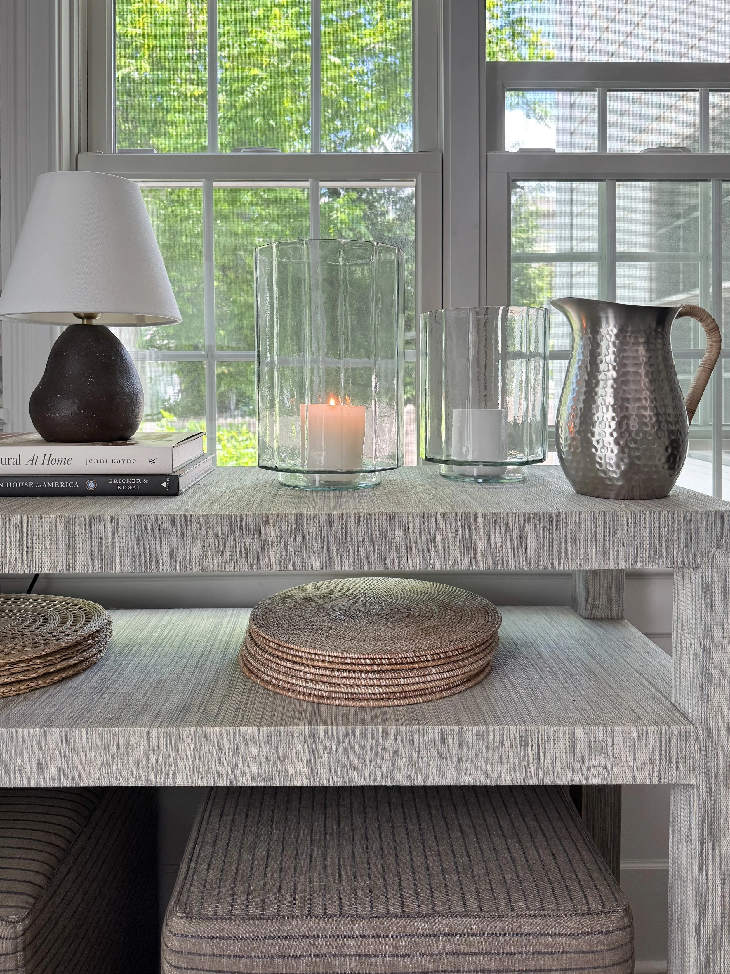 Styled dining room console featuring glass hurricane candle holders, decorative pitcher, coffee table books, and McGee & Co inspired home decor accessories.
