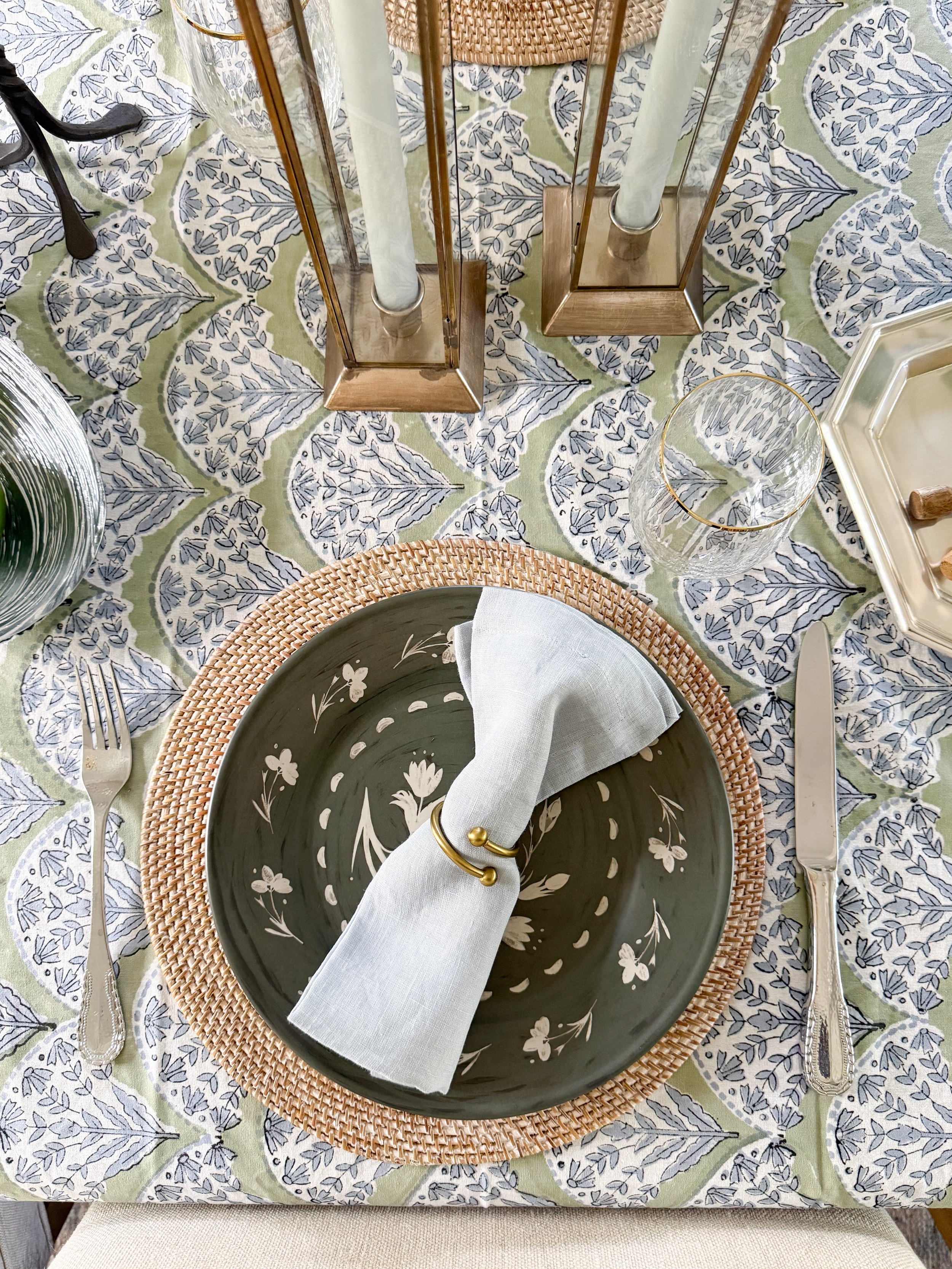 Layered McGee and Co place setting with woven placemat, floral dinner plate, linen napkin, and gold napkin ring for an elevated tablescape