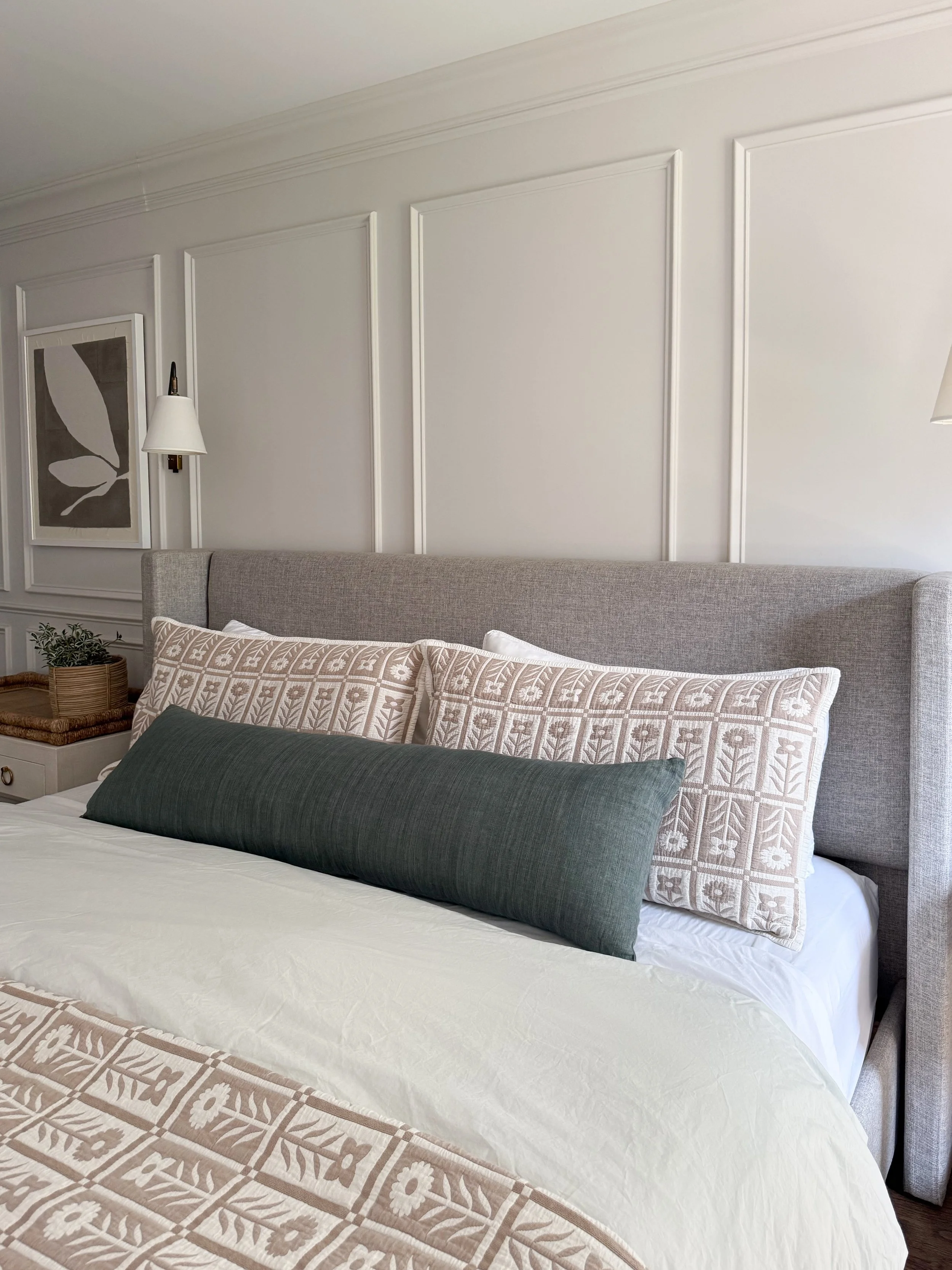 Layered Quince bedding with linen duvet, floral quilt, and decorative pillows in a bright and cozy bedroom.