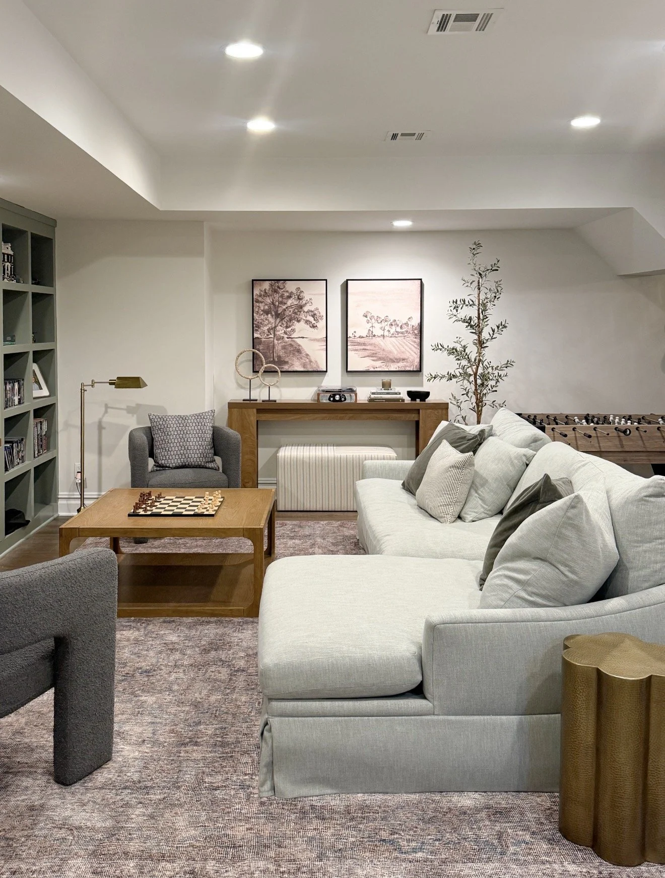 Basement media room with Benjamin Moore White Dove walls, neutral sectional sofa, wood coffee table, and cozy lounge seating in a warm neutral basement design.