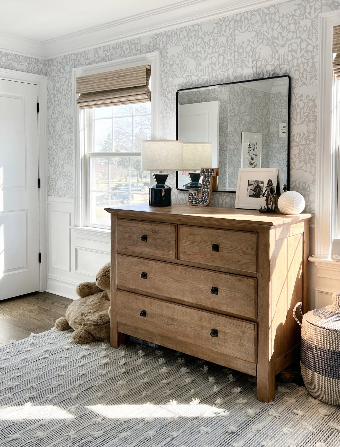 Kids bedroom with patterned wallpaper, wood dresser, and neutral decor with Benjamin Moore Chantilly Lace trim and warm natural textures.
