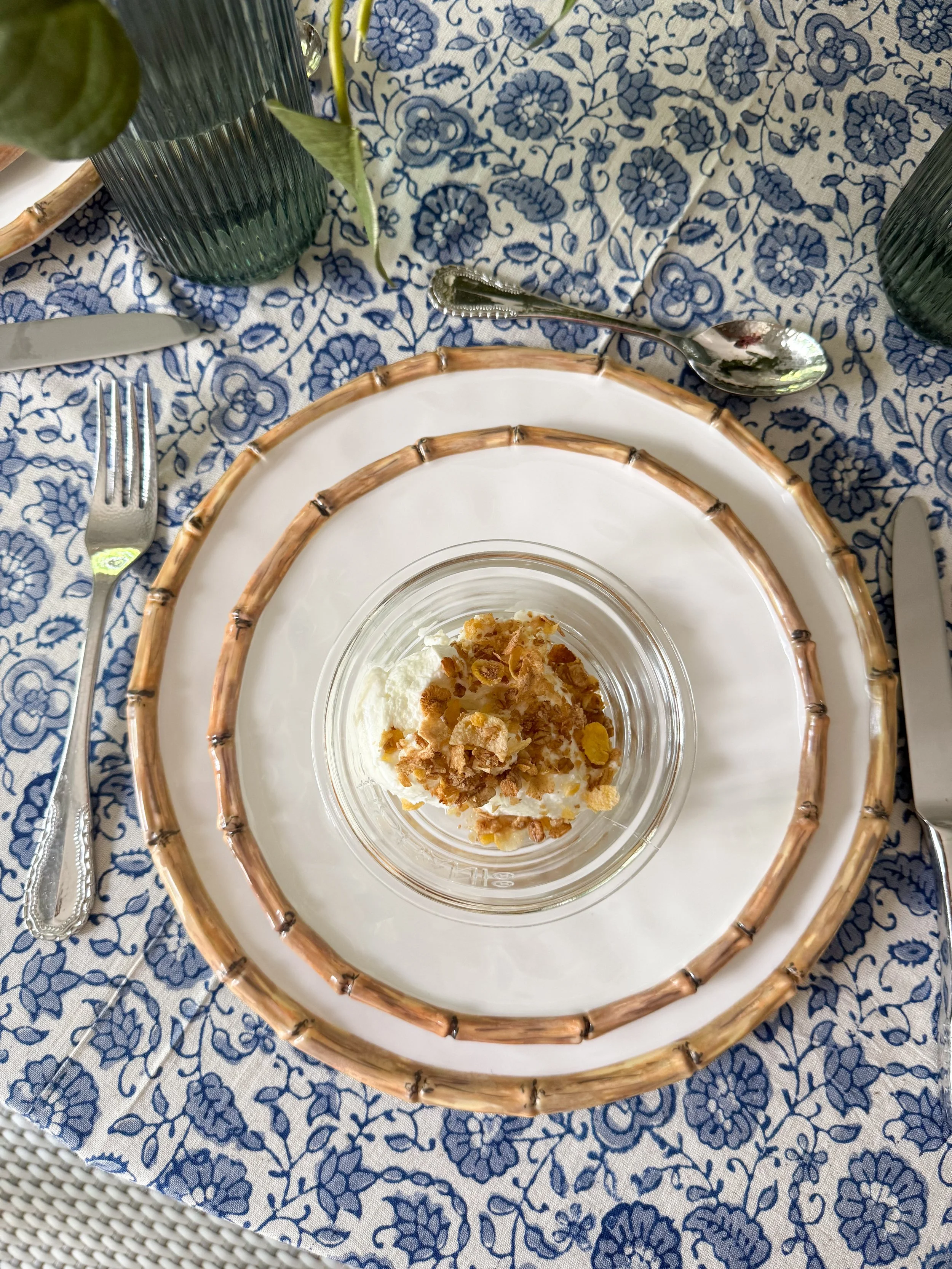 Layered summer place setting with bamboo rim dinnerware, textured glass bowls, blue glassware, and elegant tabletop decor inspired by McGee & Co entertaining style.