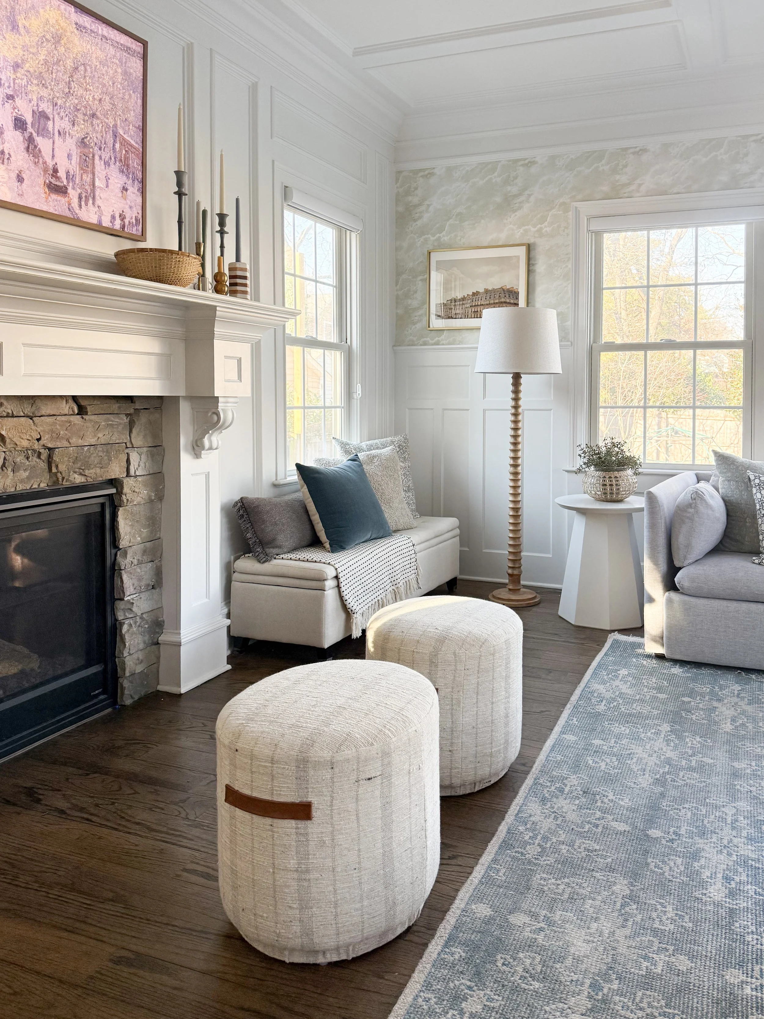 Modern wood floor lamp with a white linen shade styled beside a window in a bright neutral living room.