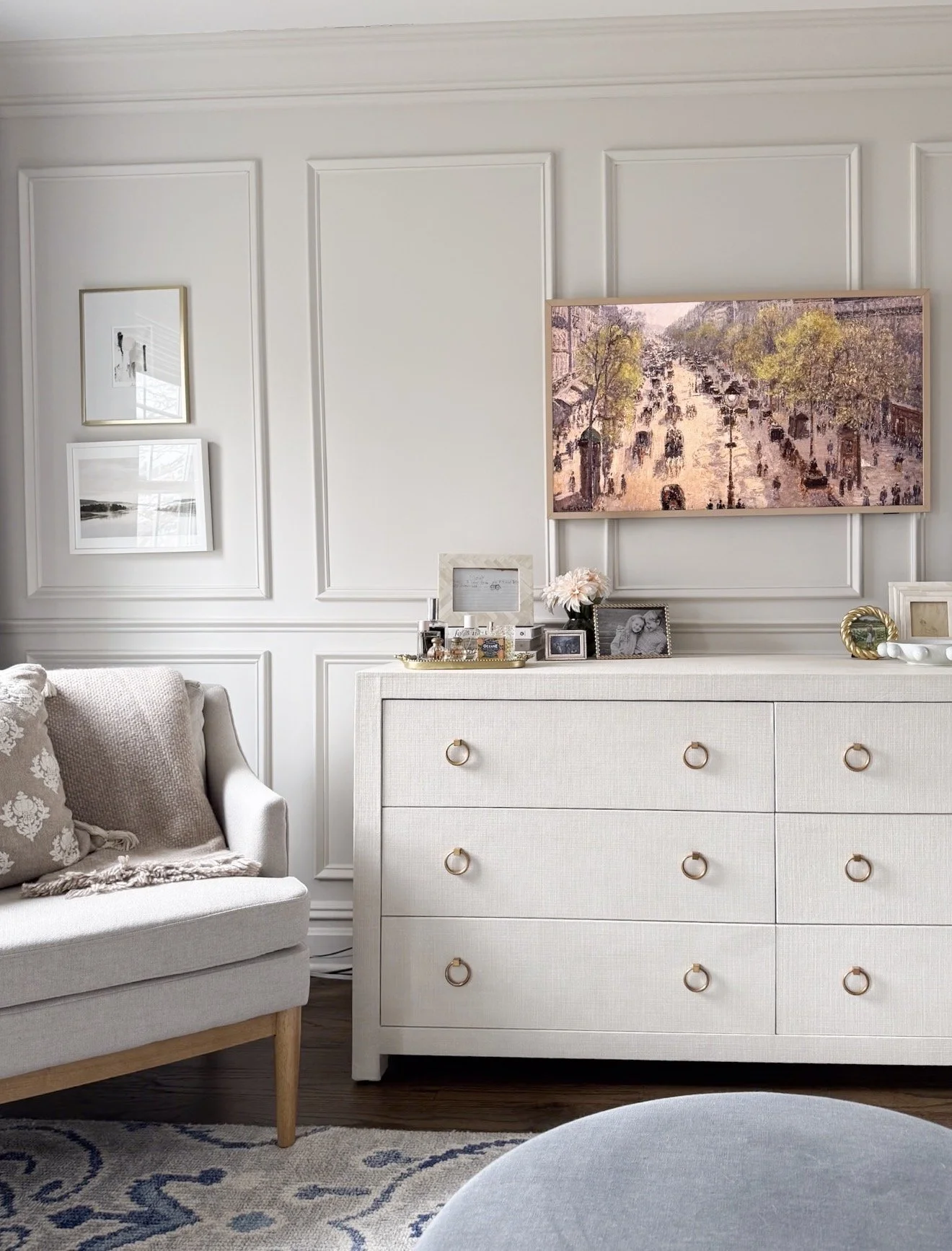 Serena & Lily Driftway dresser in a bright primary bedroom with a gray patterned rug underneath, topped with decorative vases, framed artwork, and a gold table lamp, paired with neutral bedding and curtains."