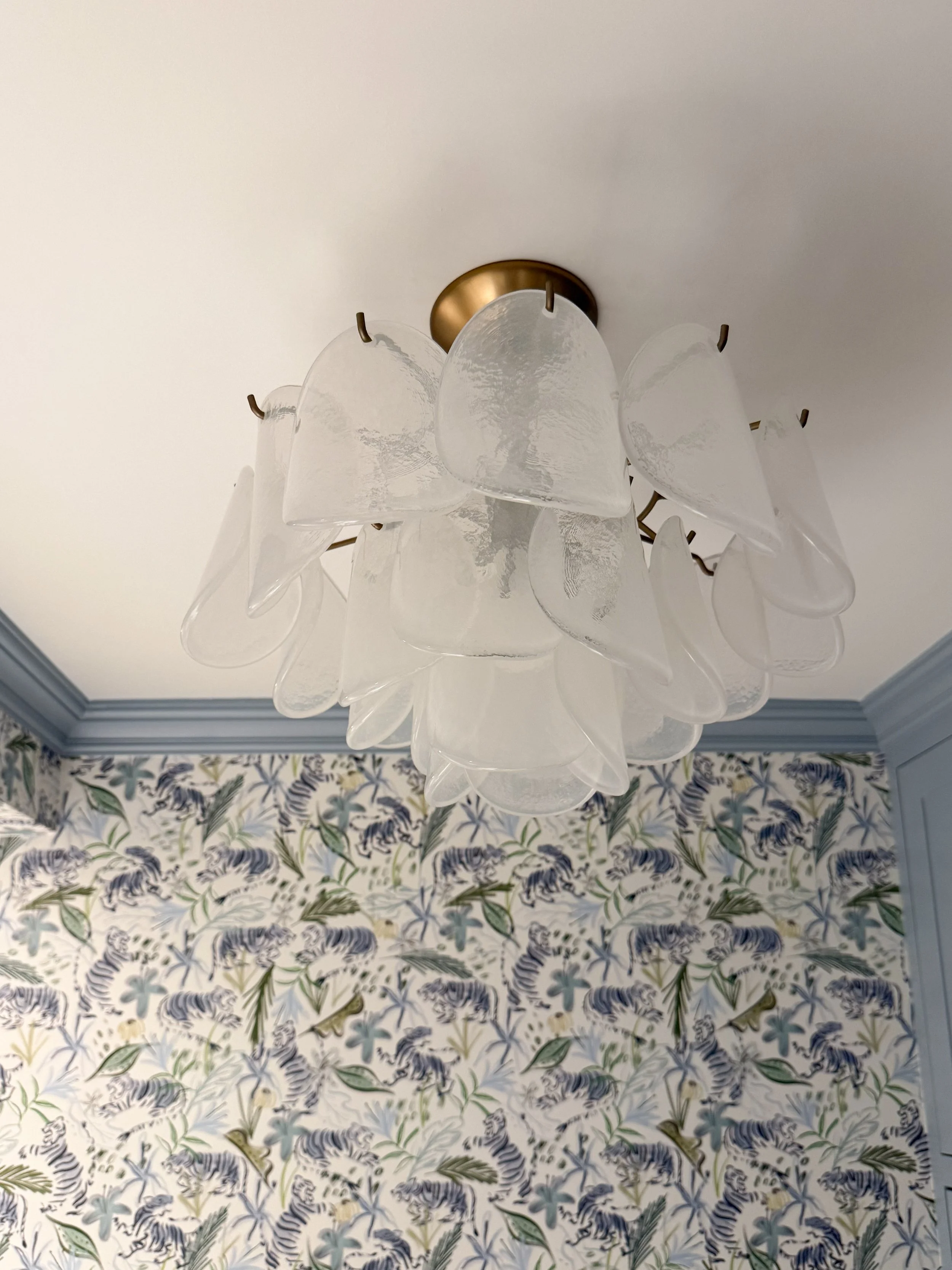 Decorative glass semi flushmount ceiling light sparkling against blue tiger wallpaper in a colorful powder room.