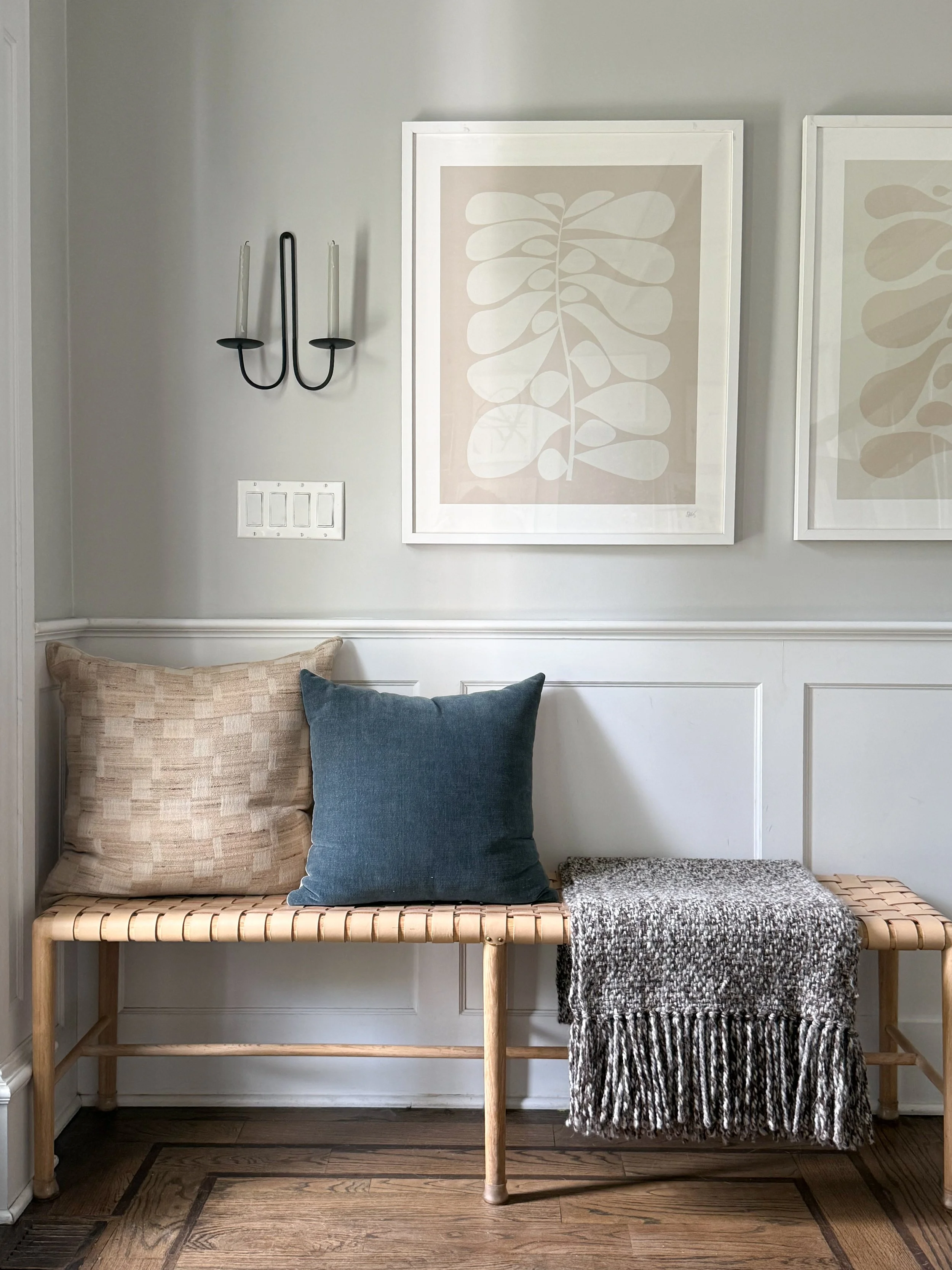 Styled entryway bench layered with throw pillows, a cozy blanket, and decorative accents for a warm, inviting entry.