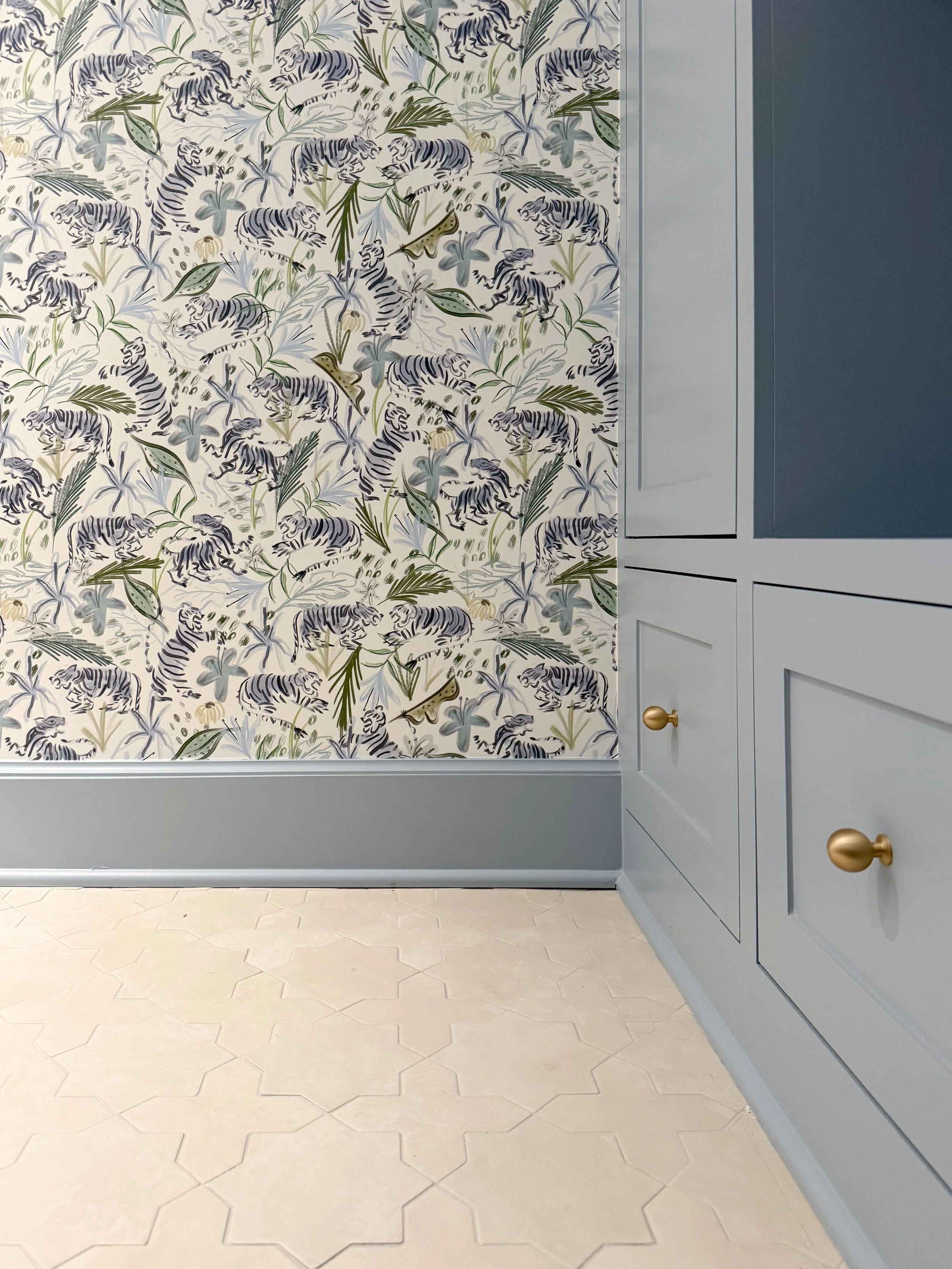 Blue Manor Blue cabinetry paired with patterned tiger wallpaper and star and cross tile flooring.