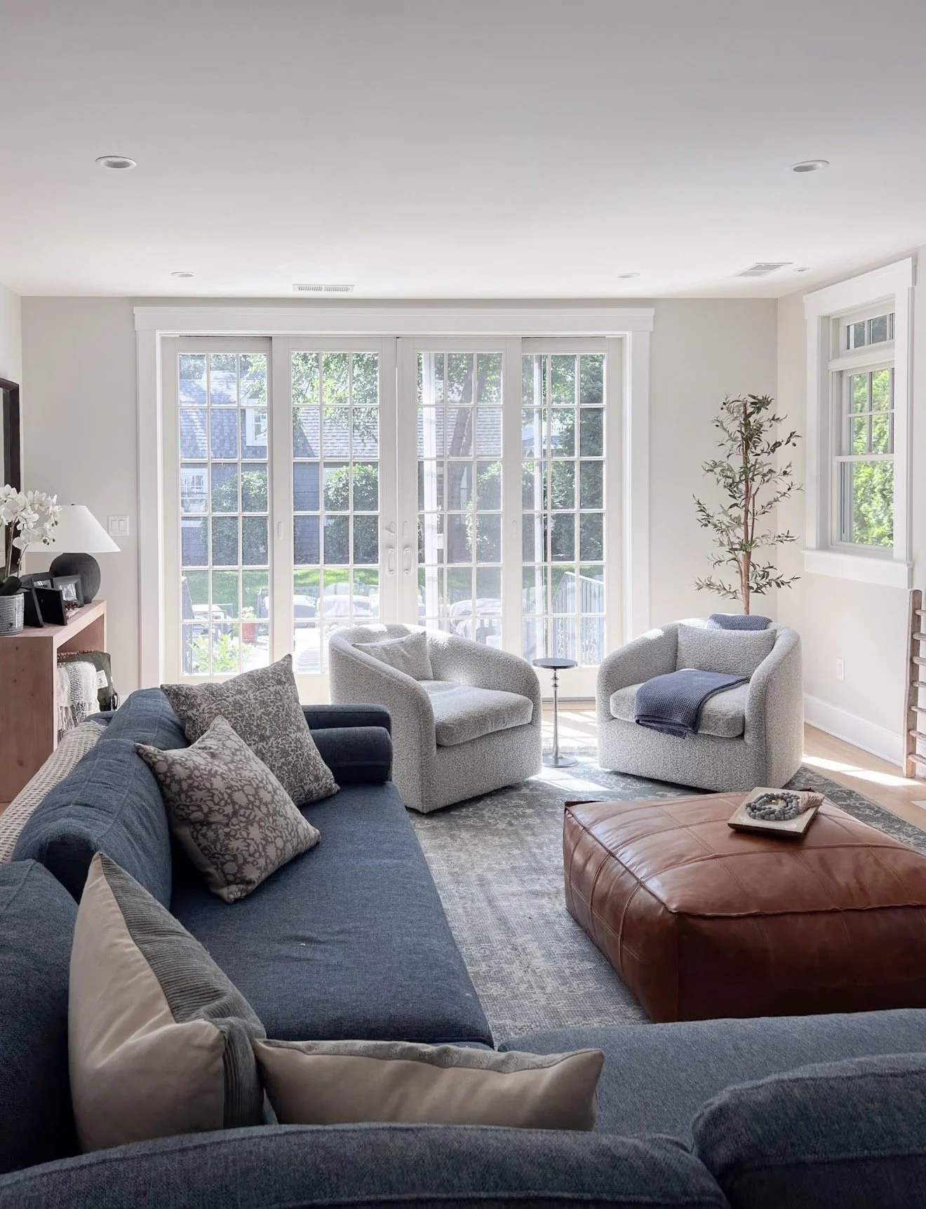 Blue sofa with layered gray floral throw pillows and a coordinating blue and gray patterned area rug.
