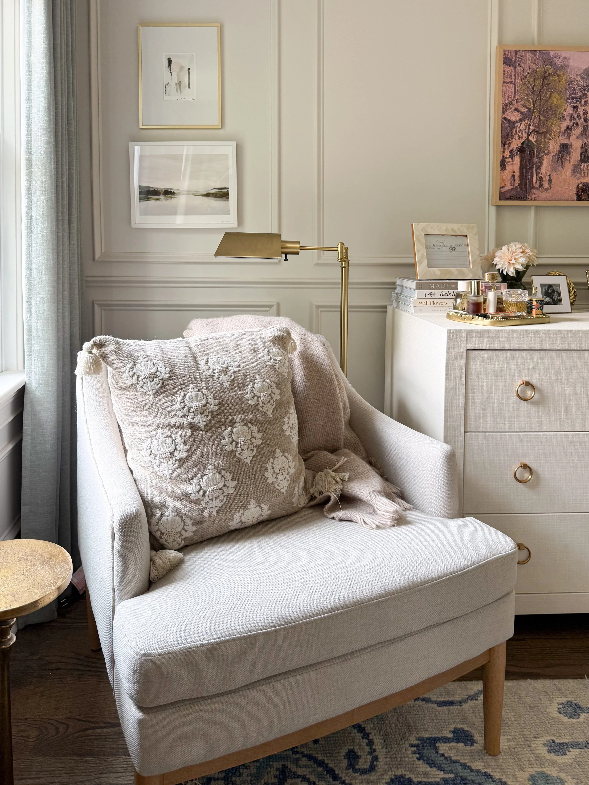 Neutral upholstered accent chair styled in a cozy bedroom reading corner with soft textures and natural light.