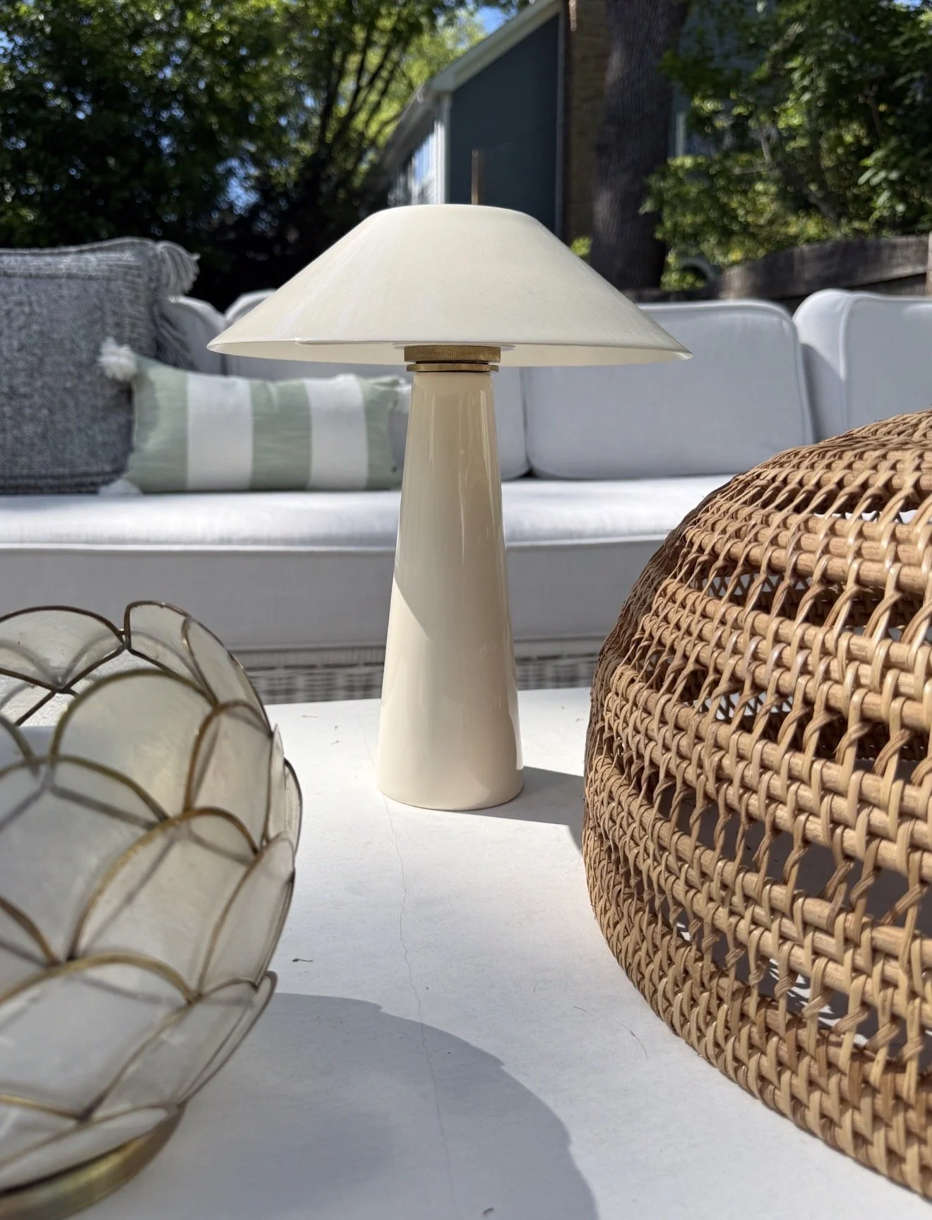 Serena & Lily cordless table lamp styled on an outdoor coffee table with candles and patio seating.