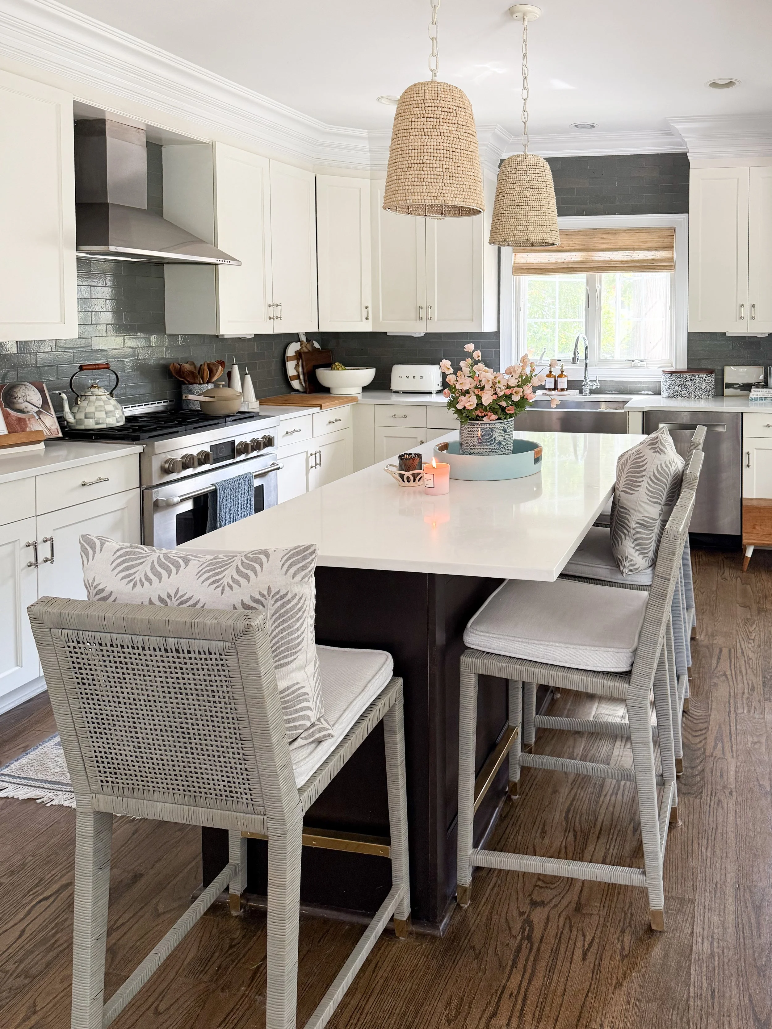 Bright white kitchen with woven pendant lights above a large island and natural texture throughout the space.