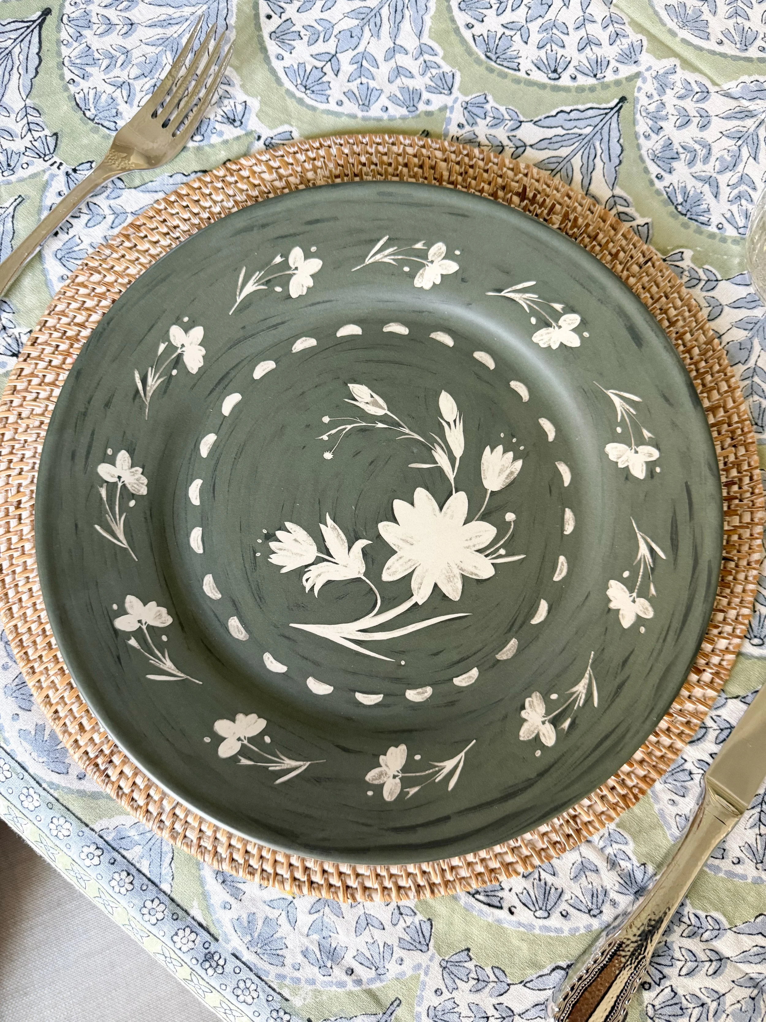 McGee and Co green floral dinner plate styled on a woven placemat with neutral linens for a layered tablescape