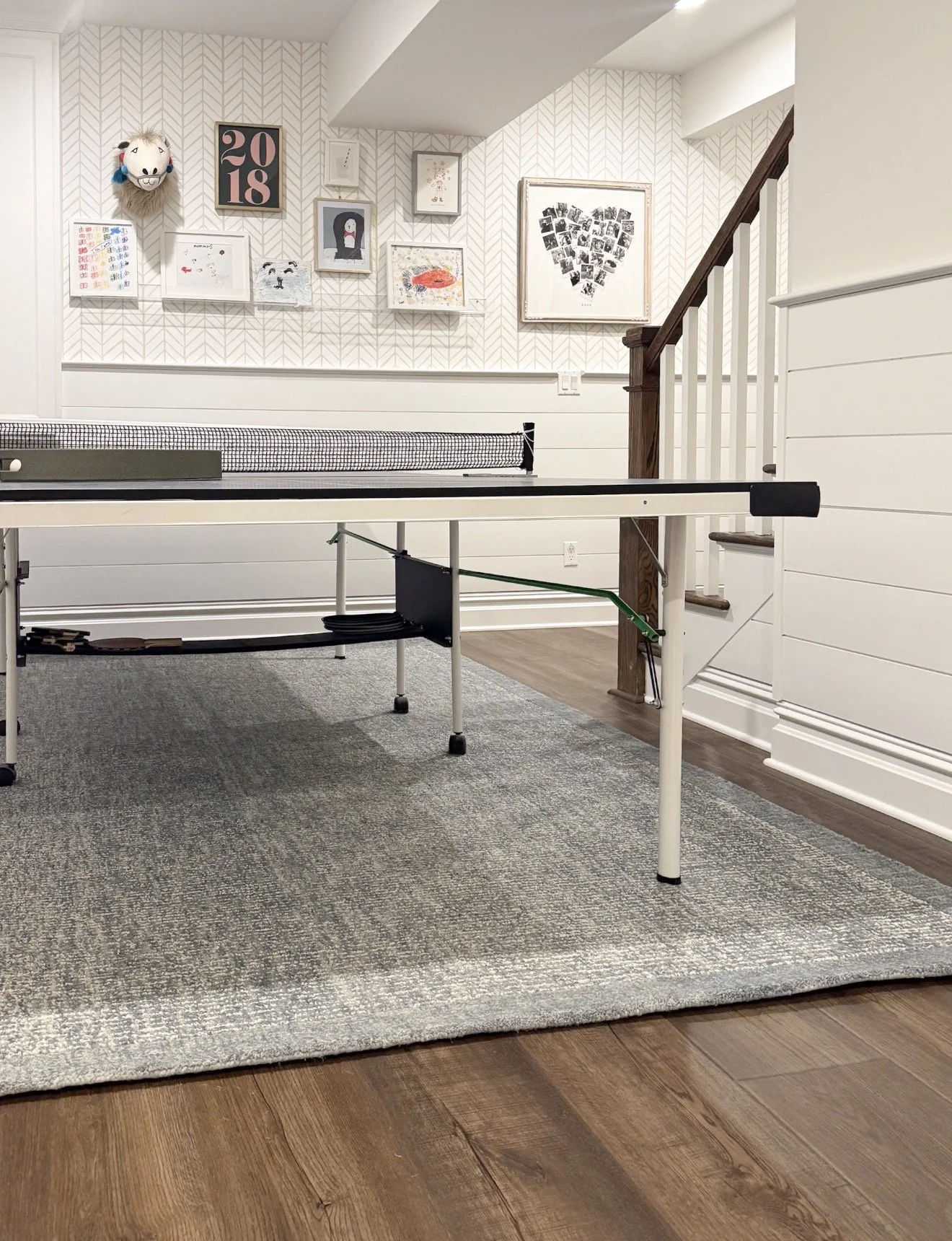 Game room with a ping pong table, gallery wall, white paneling, and a textured neutral Loloi area rug.