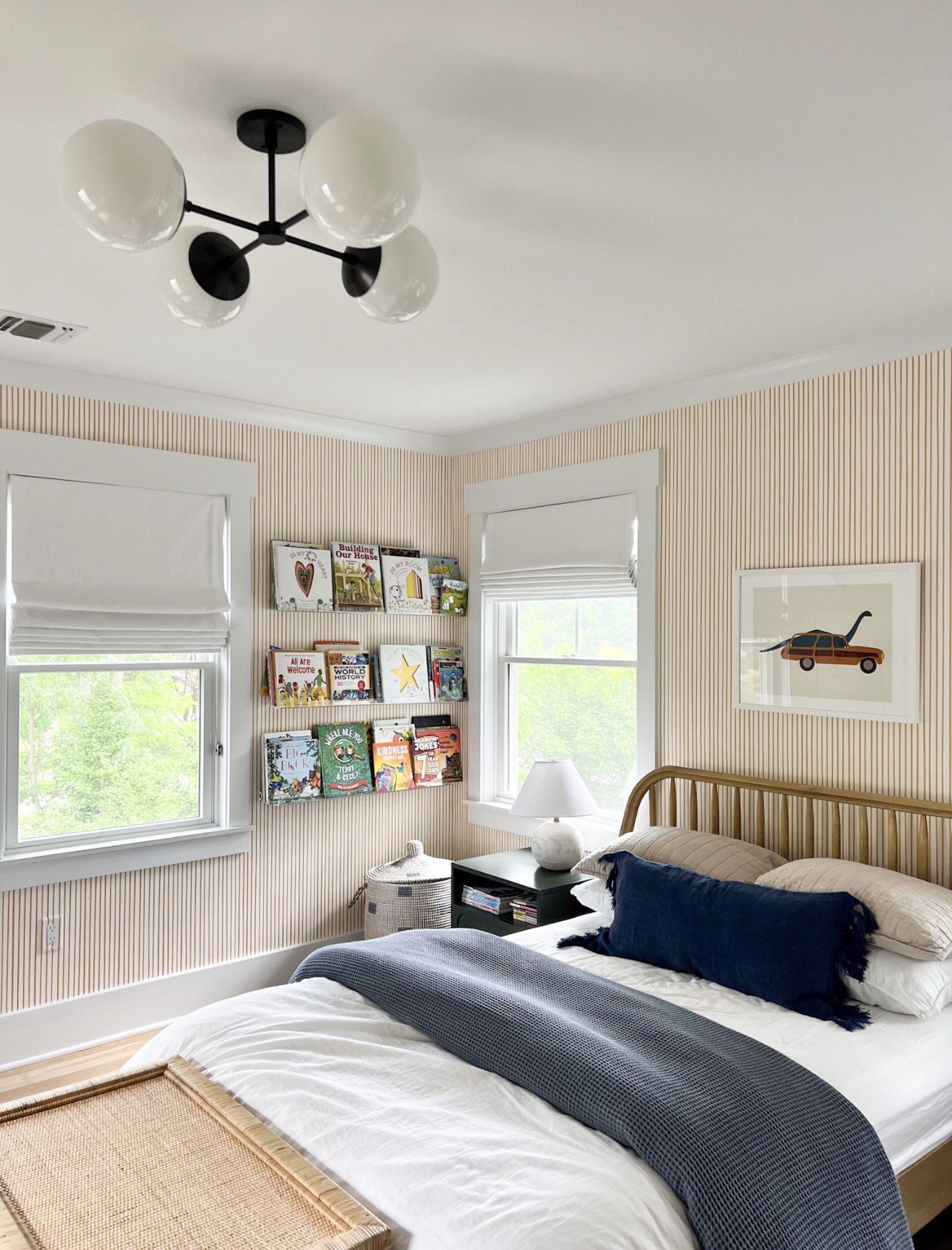 Kids bedroom with vertical striped wallpaper, wooden bed frame, and wall mounted book display