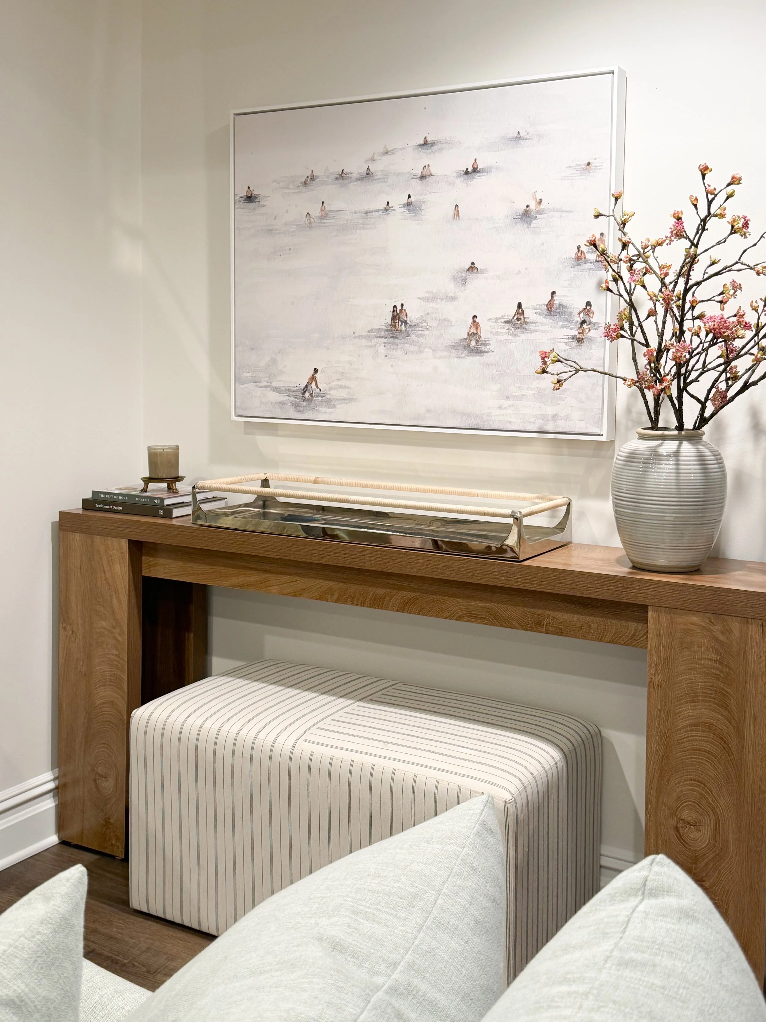 basement console styling, warm wood furniture, oversized framed art, neutral basement decor, coastal inspired interiors, styled console table, layered home decor, soft neutral basement, cozy family room decor, modern organic basement