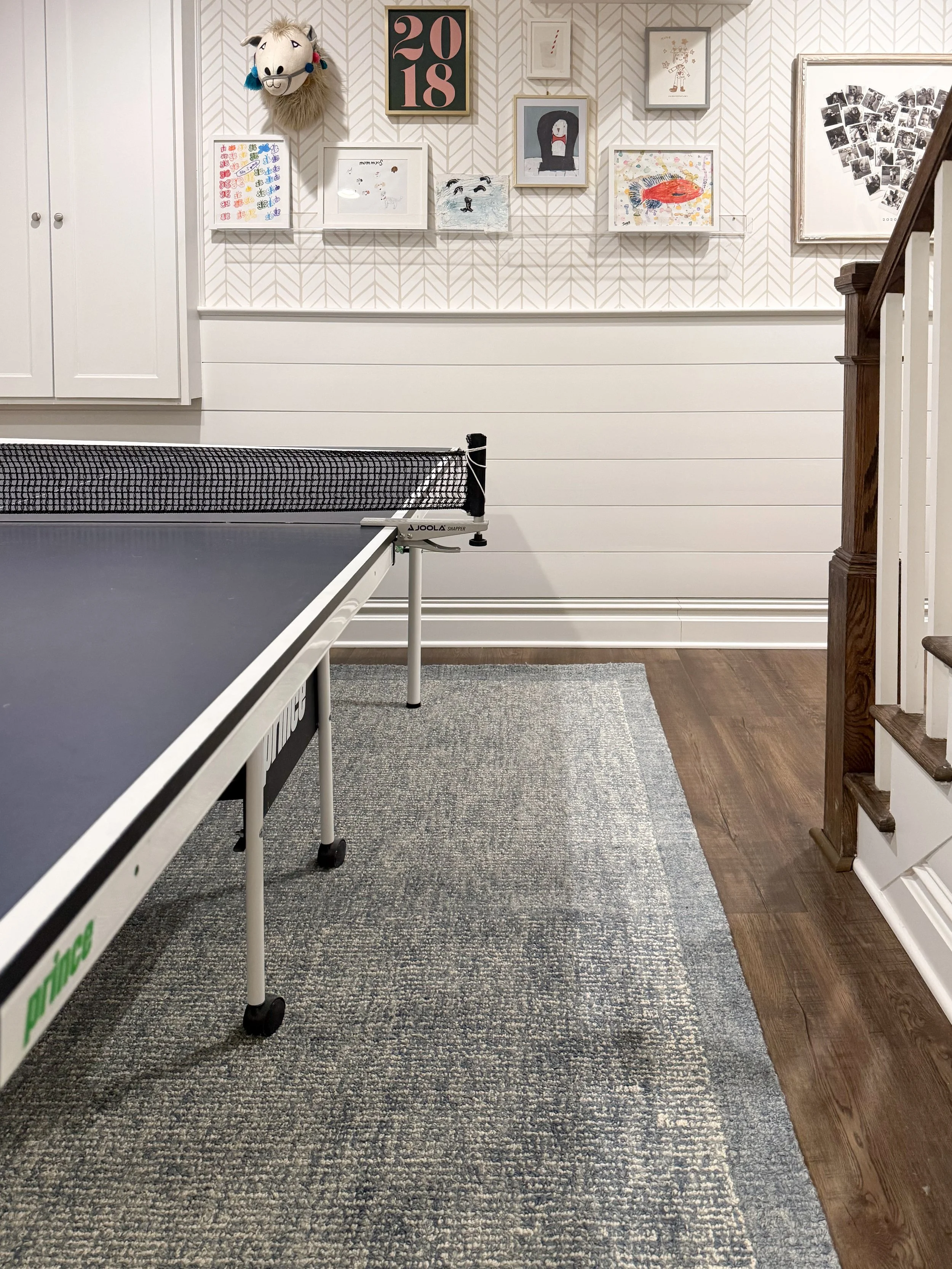 Basement game room featuring a ping pong table, neutral area rug, and modern family entertainment space.