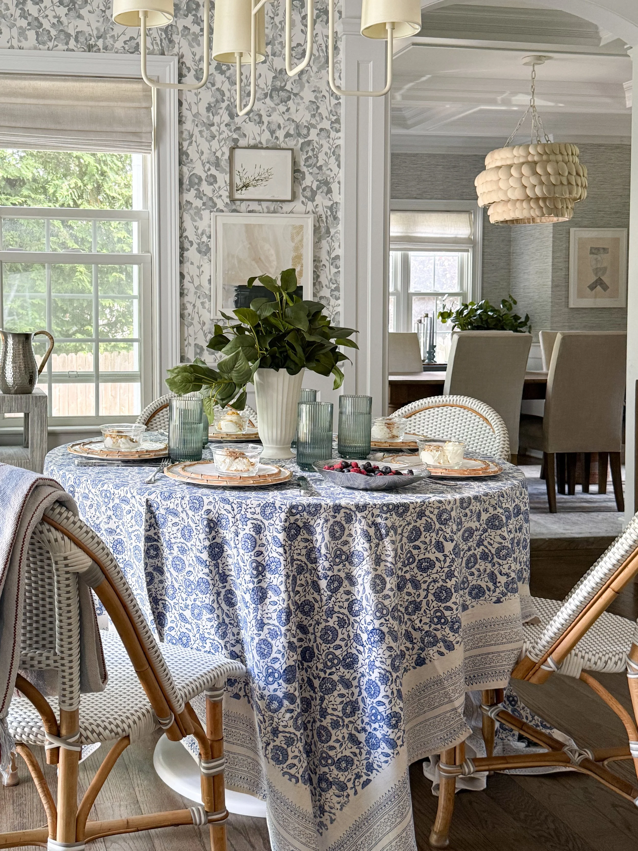 Blue and white summer tablescape with McGee & Co decor, patterned tablecloth, bamboo dinnerware, glassware, candles, and greenery centerpiece for casual entertaining at home.