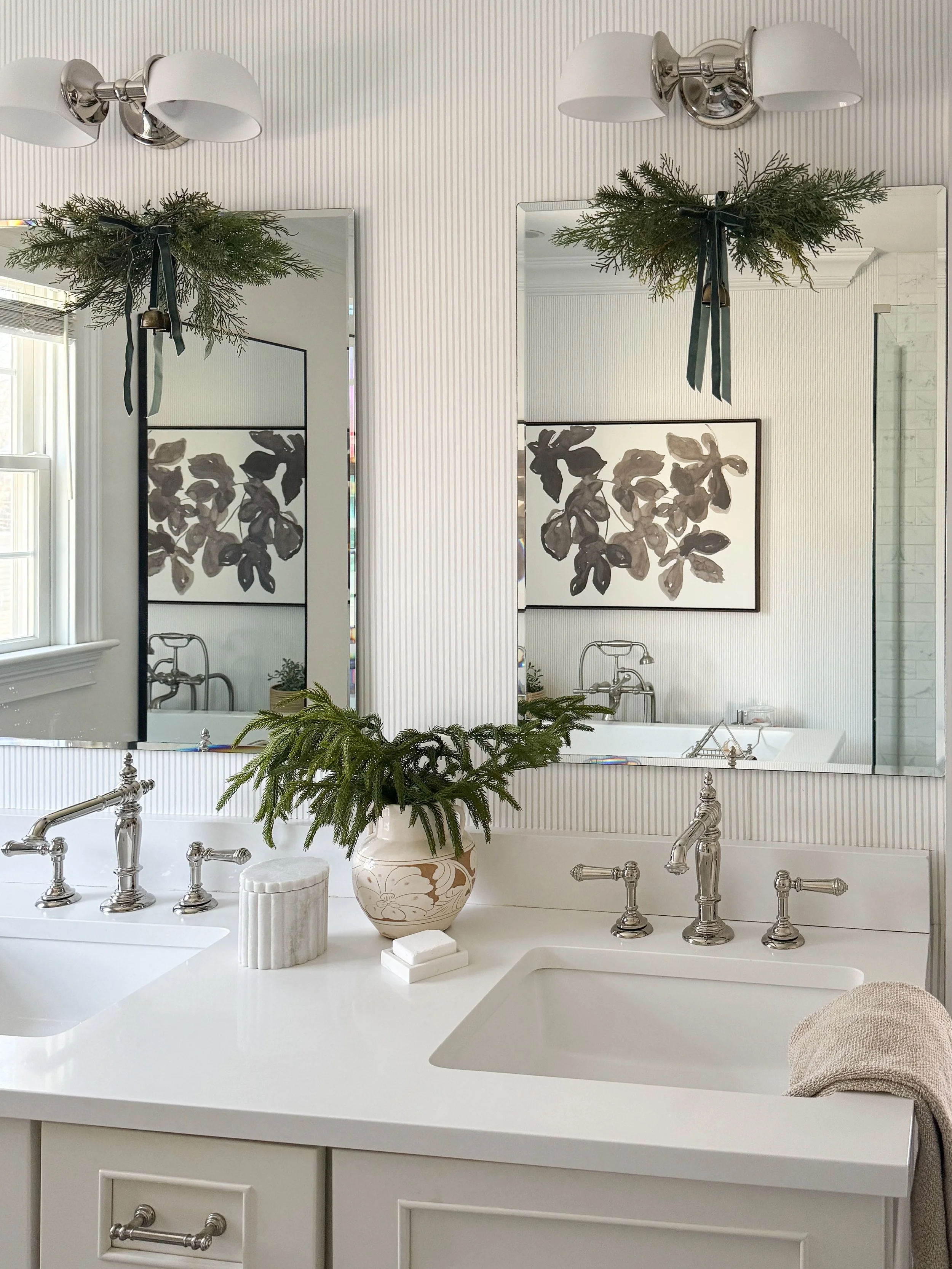 Primary bathroom featuring polished nickel double vanity sconces above framed mirrors and a white double sink.