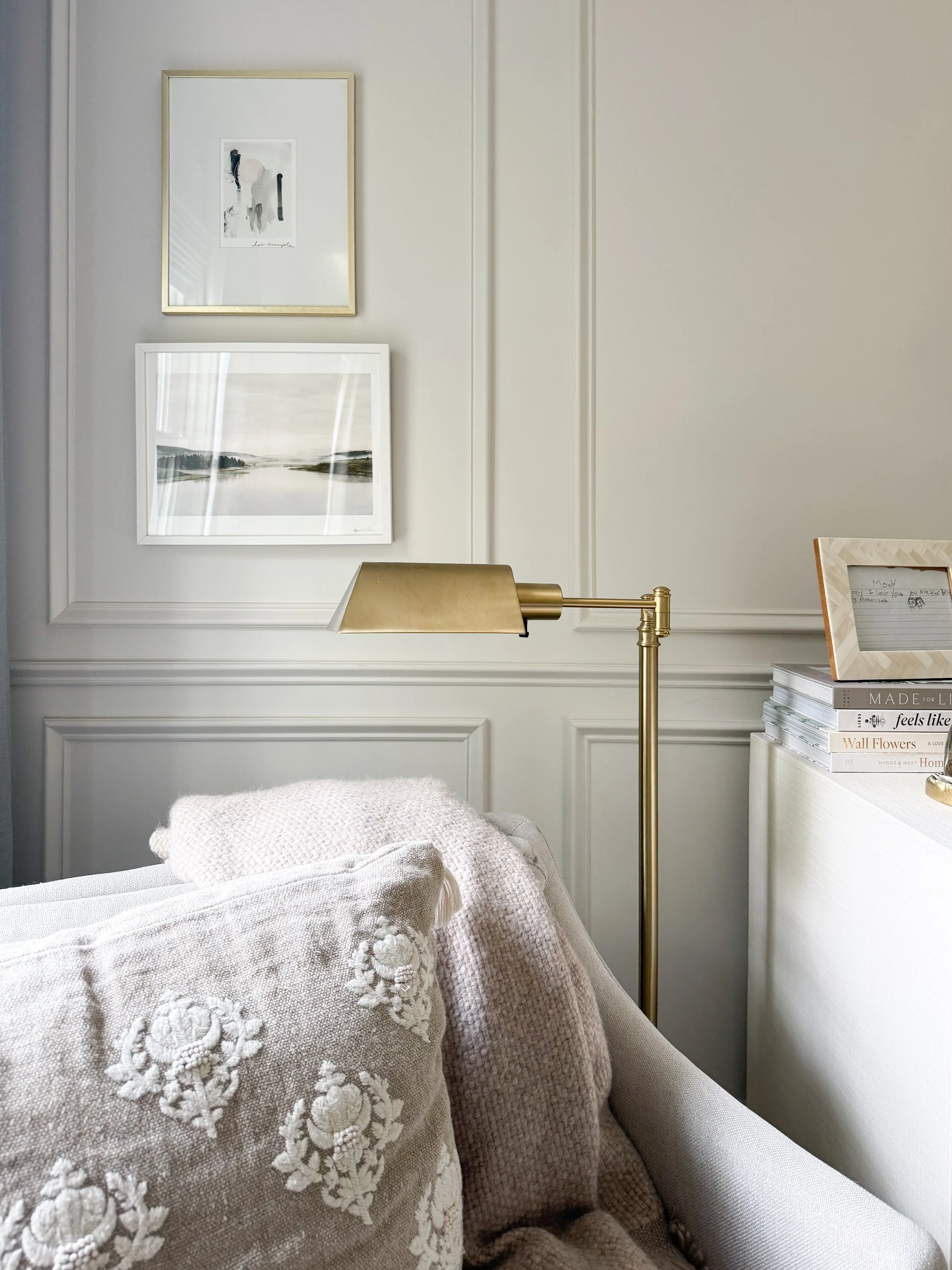 Brass floor lamp beside a cozy accent chair with a throw blanket and decorative pillow in a bedroom reading nook.