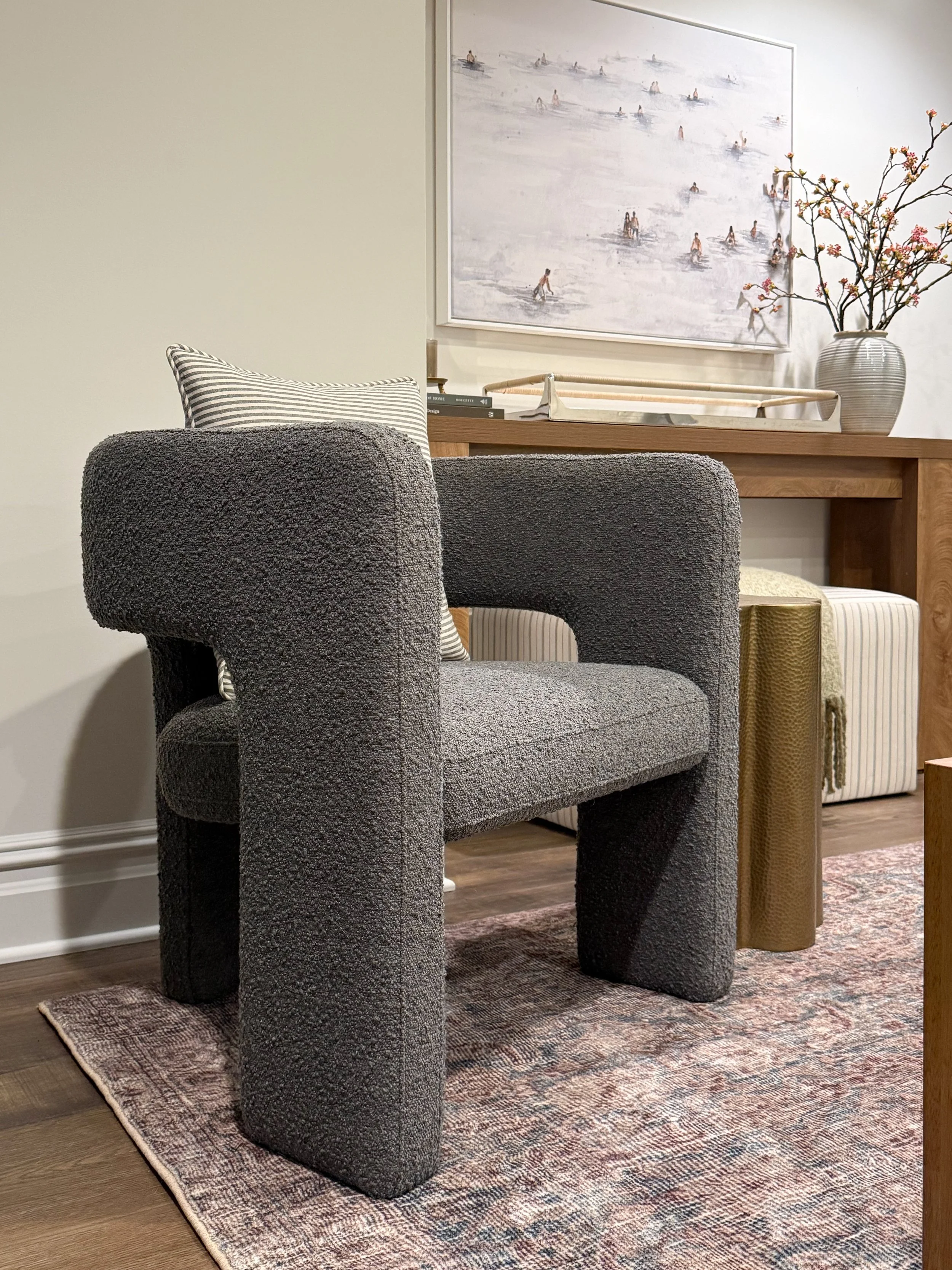 Neutral accent chair paired with a side table in a cozy living room reading nook with warm textures.