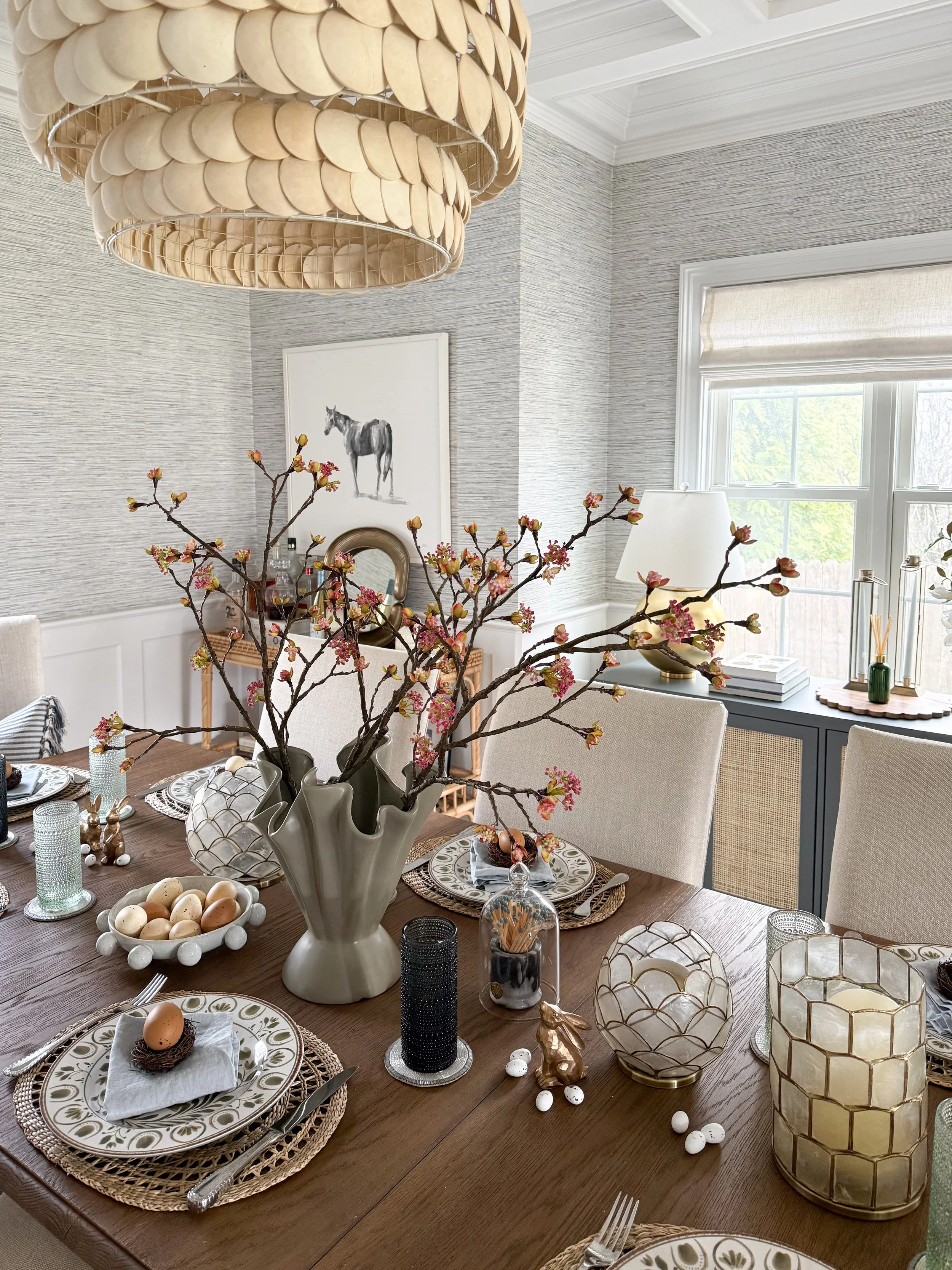 Elegant spring dining room chandelier above Easter tablescape with neutral tones, blooming branches, and styled table setting