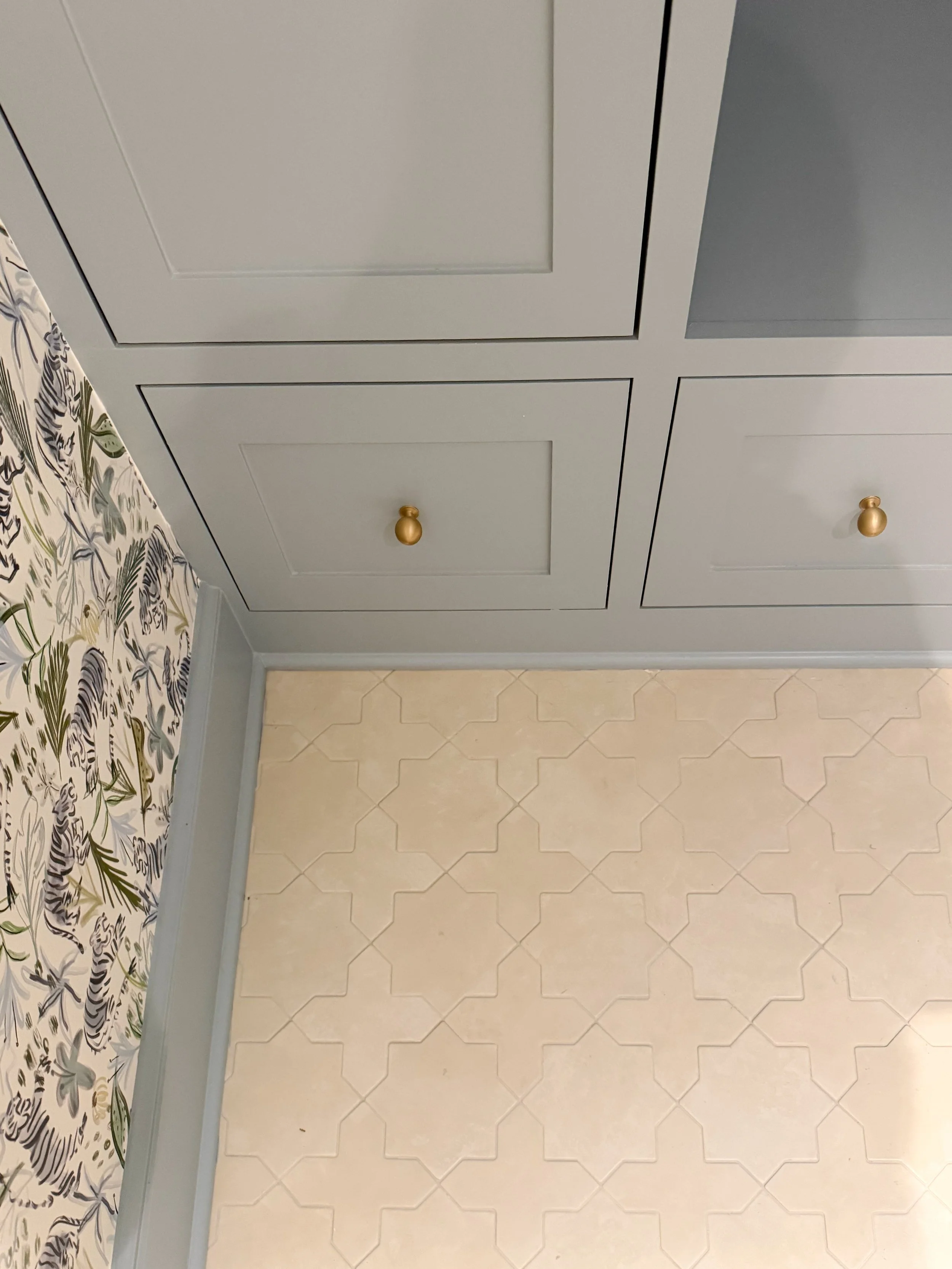 Star and cross floor tile with tonal grout beside a natural wood vanity in a blue powder room.