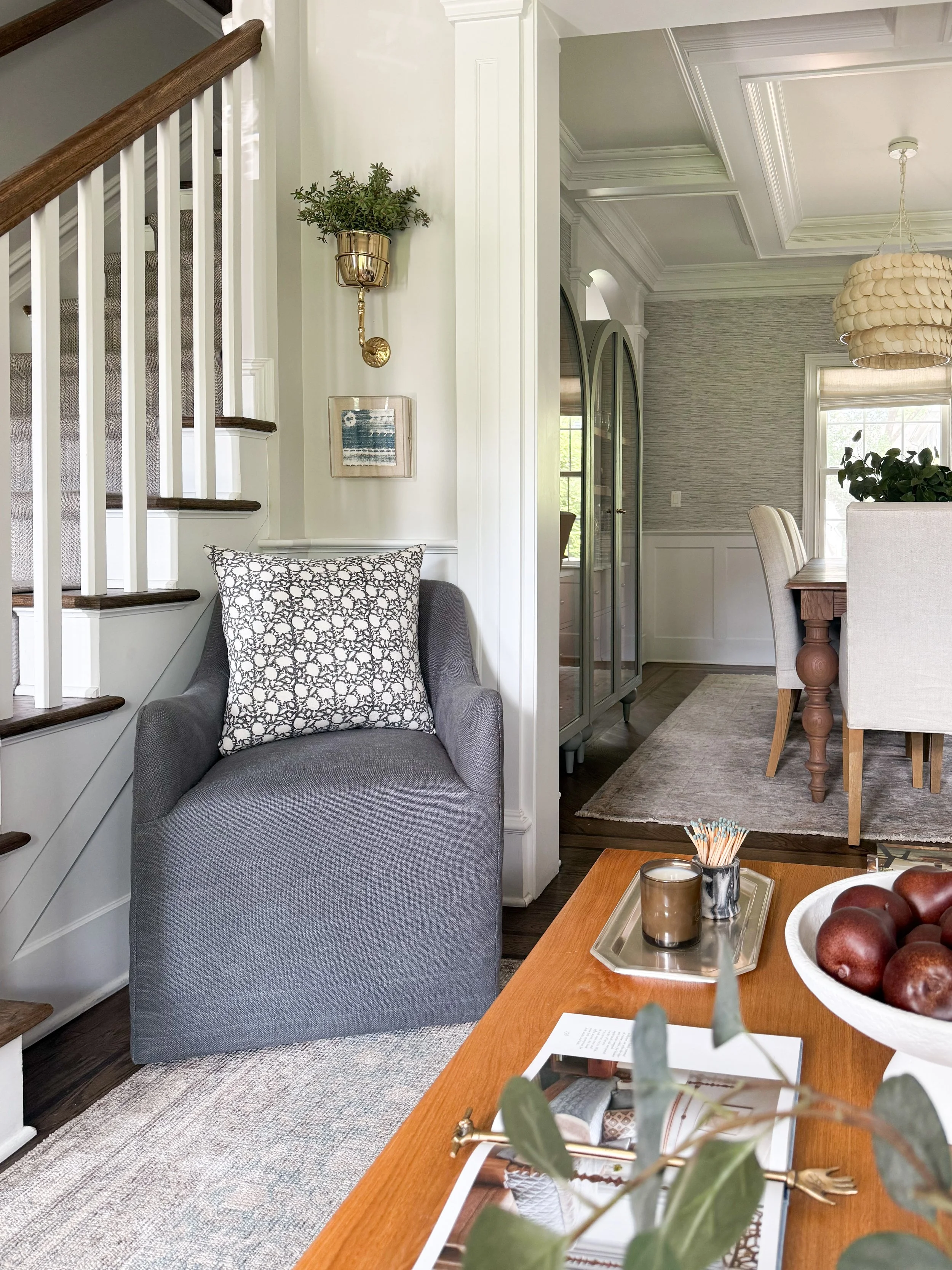 Cozy den reading nook featuring an accent chair, wall sconce, artwork, and layered home décor.