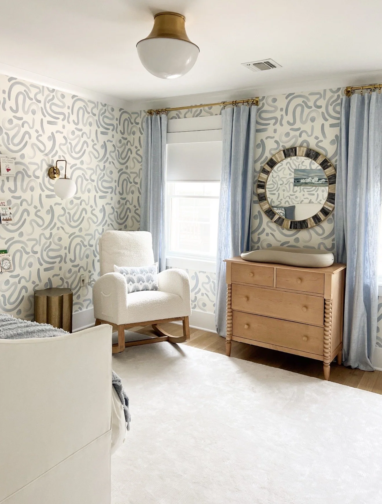 Kids room with blue abstract wallpaper, light wood dresser, and cozy reading chair