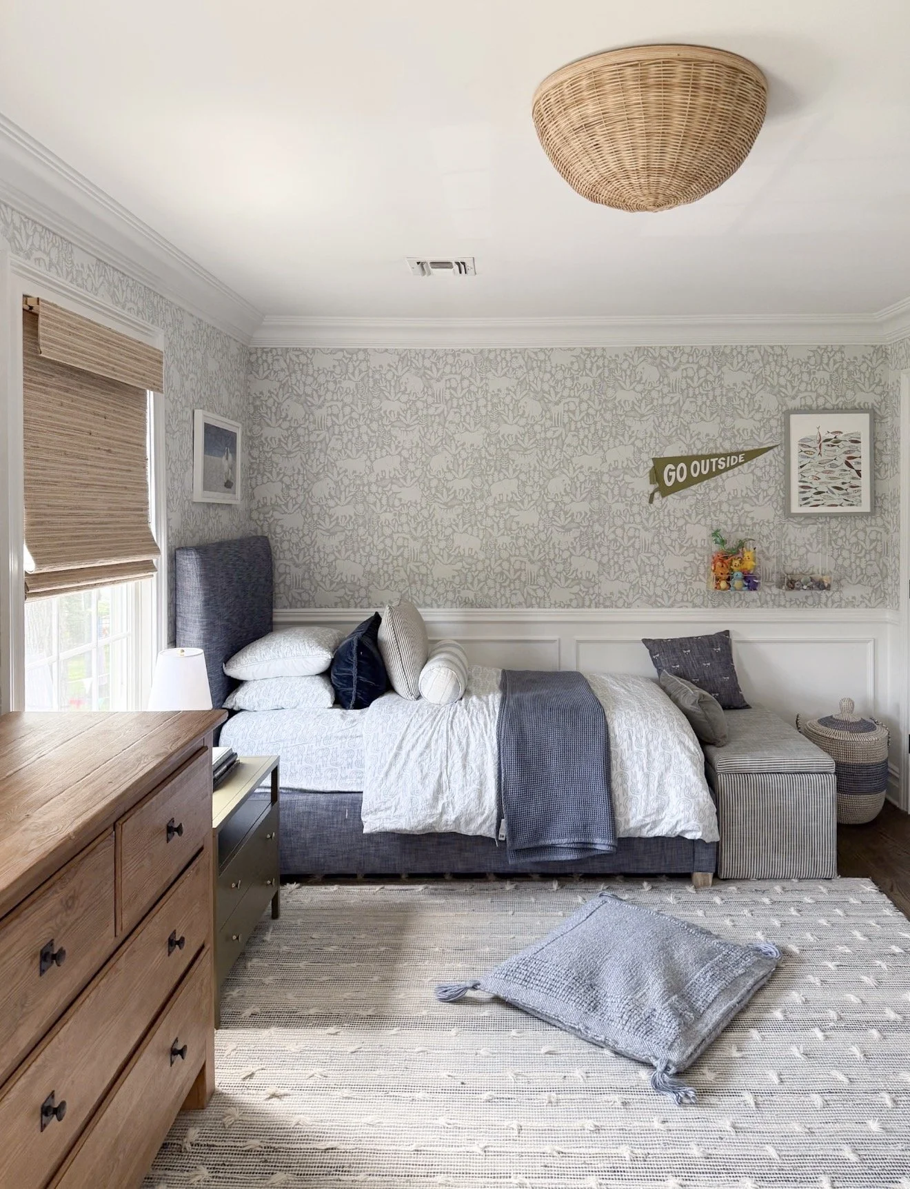 Kids bedroom with neutral jungle animal wallpaper, upholstered bed, and layered neutral textiles