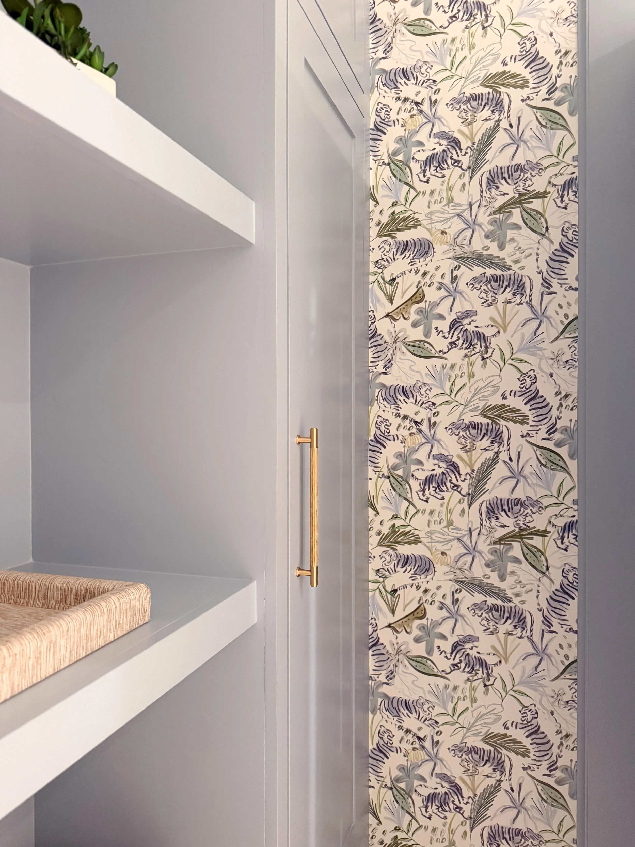 Manor Blue built in cabinetry and open shelving surrounded by colorful tiger wallpaper in a client powder room.