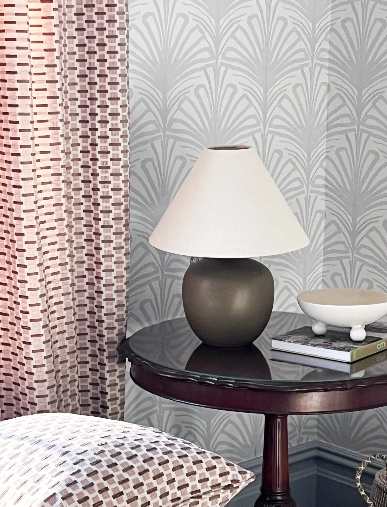 Close-up of blue botanical wallpaper, patterned woven basket, neutral rug, and natural woven lamp shade.