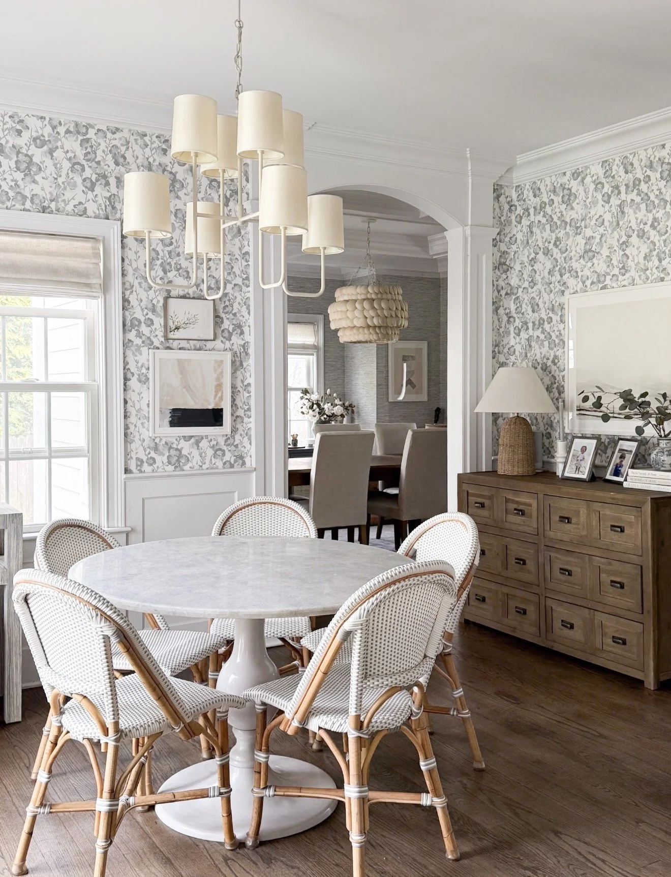 Bright breakfast nook featuring Serena & Lily South Seas wallpaper, bistro dining chairs, and a round dining table.