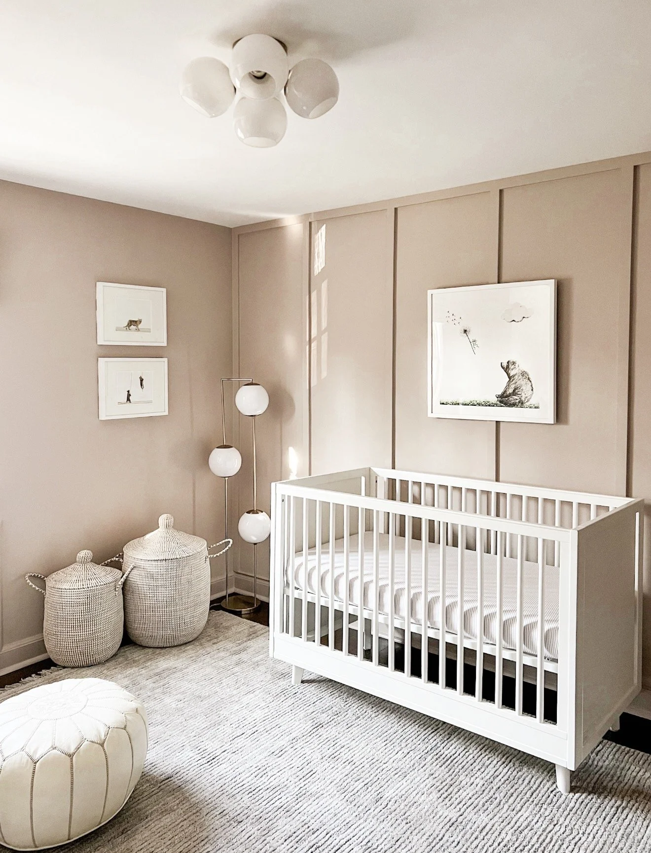 Neutral nursery with blush walls, white crib, white globe flush mount ceiling light, and textured decor accents.