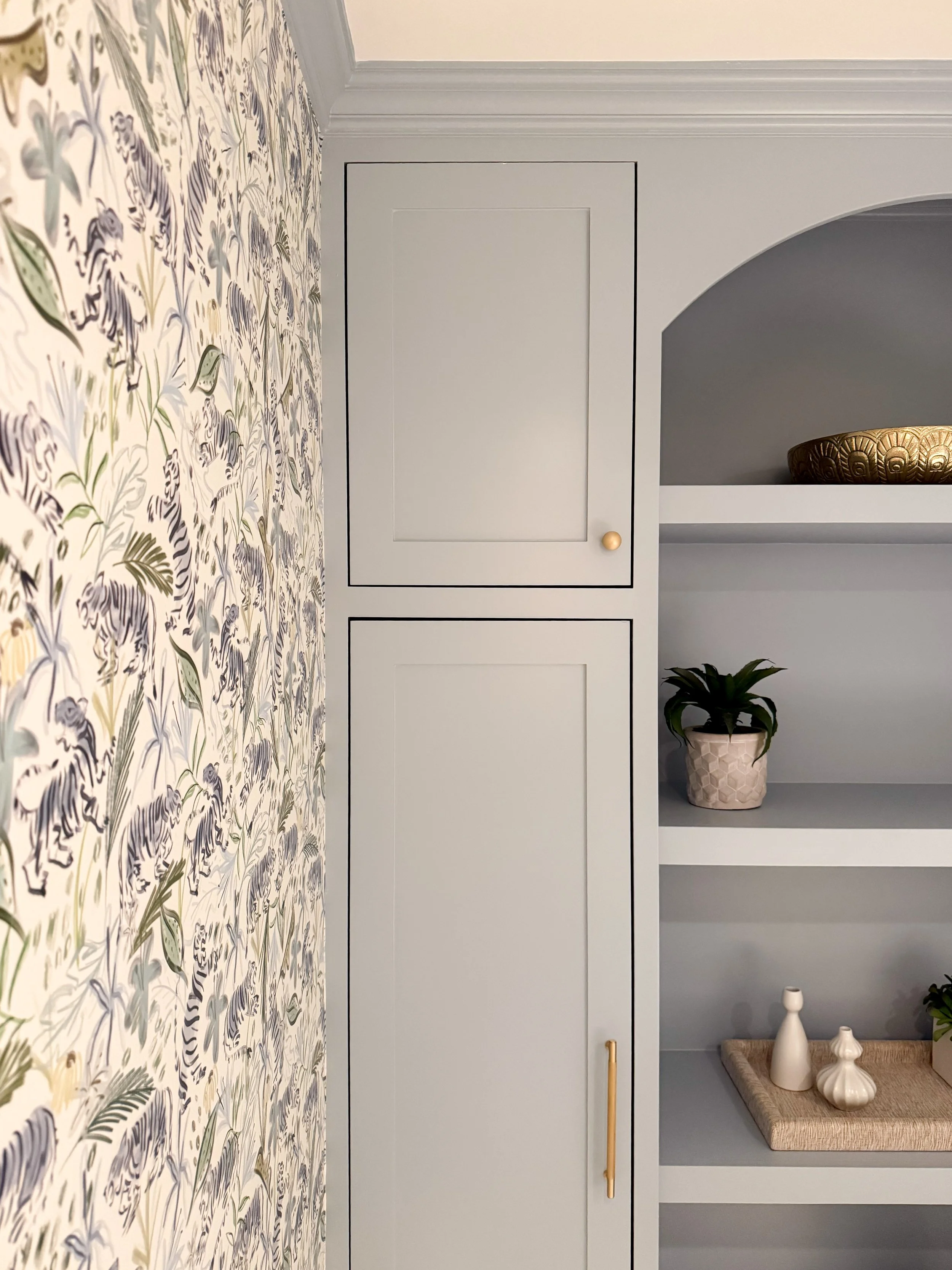 Custom blue built in storage with open shelving, brass hardware and styled accessories in a powder room.