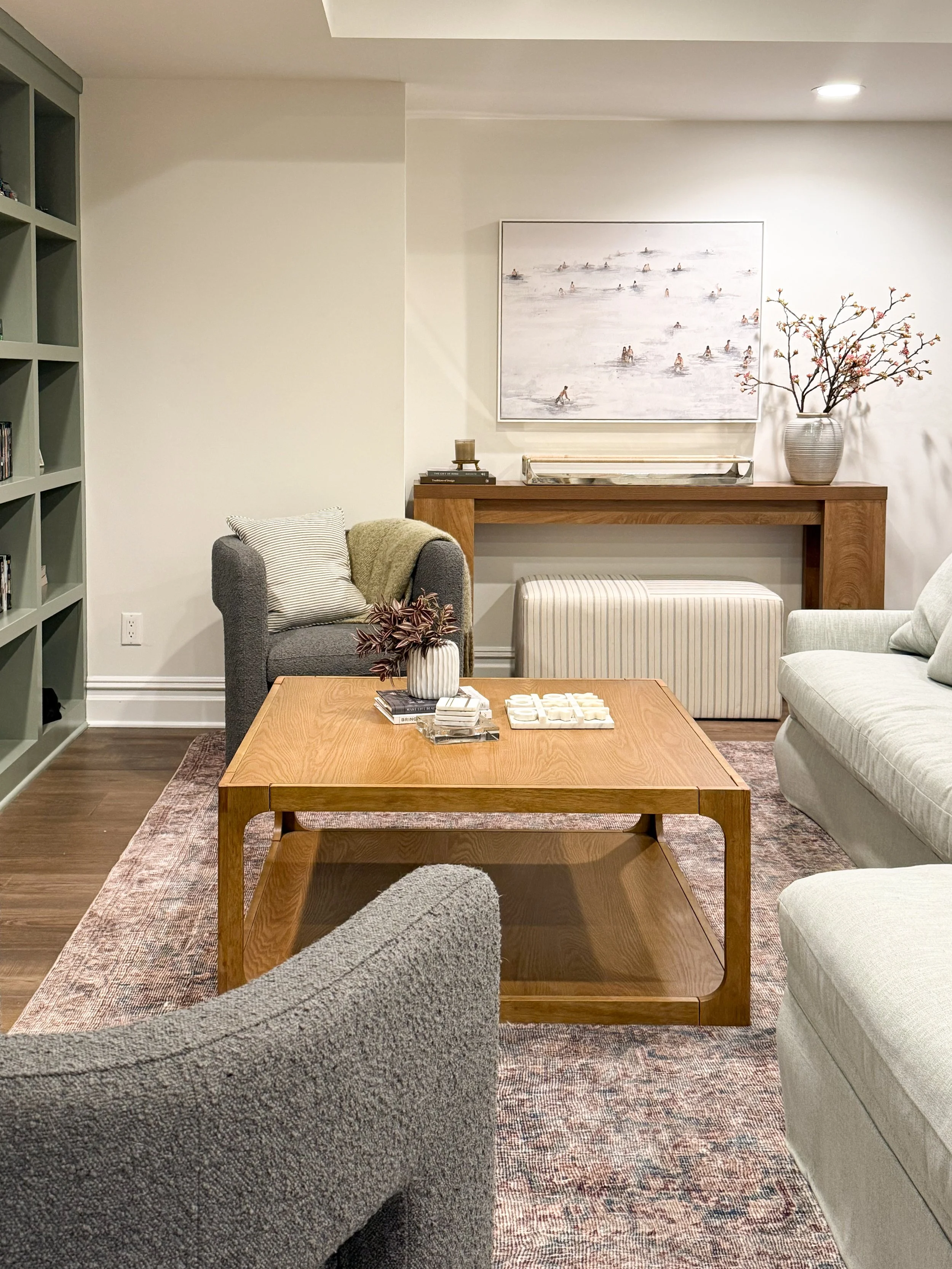 Cozy basement family room with boucle accent chairs, a neutral patterned rug, and warm layered décor.