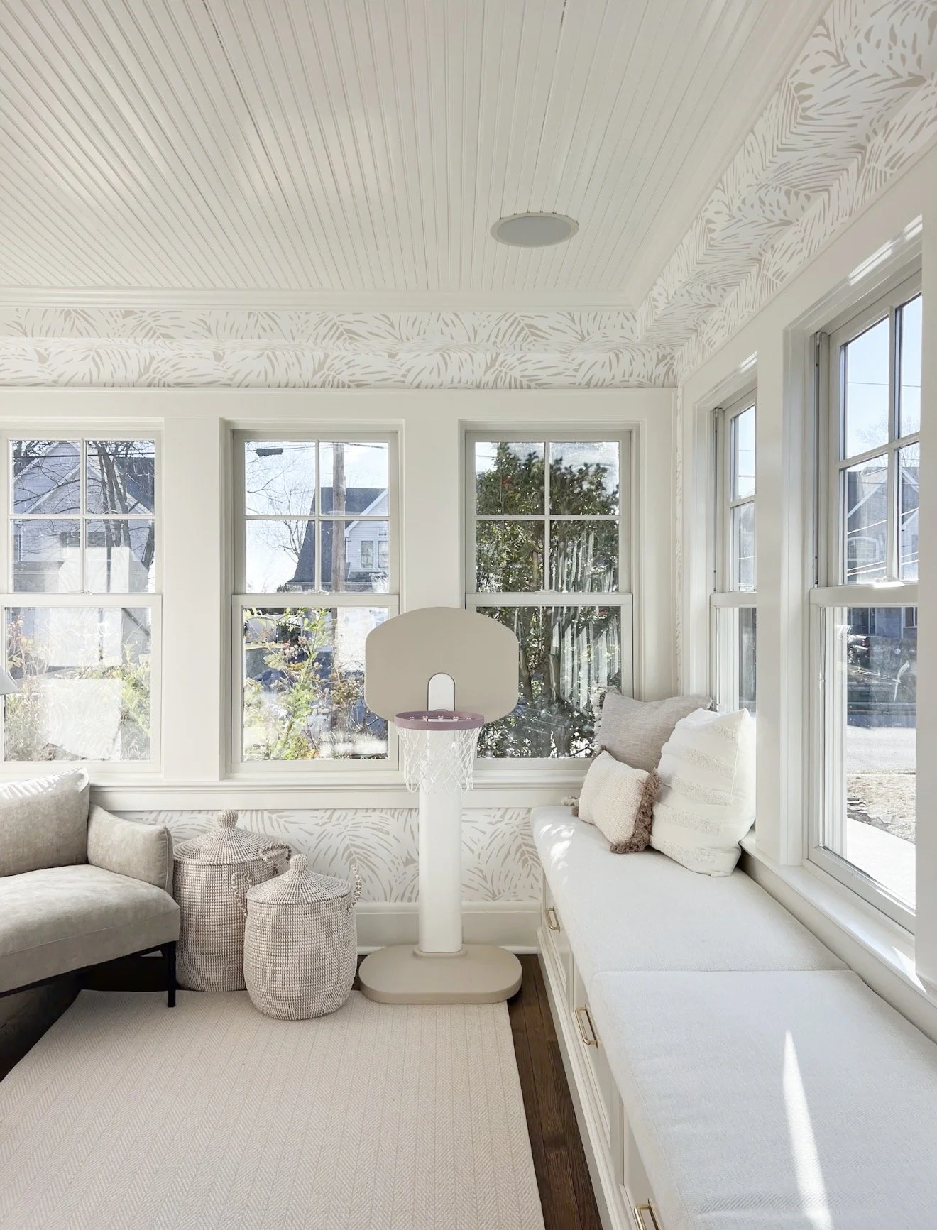 Bright sunroom with subtle wallpaper border, built in bench seating, and neutral decor