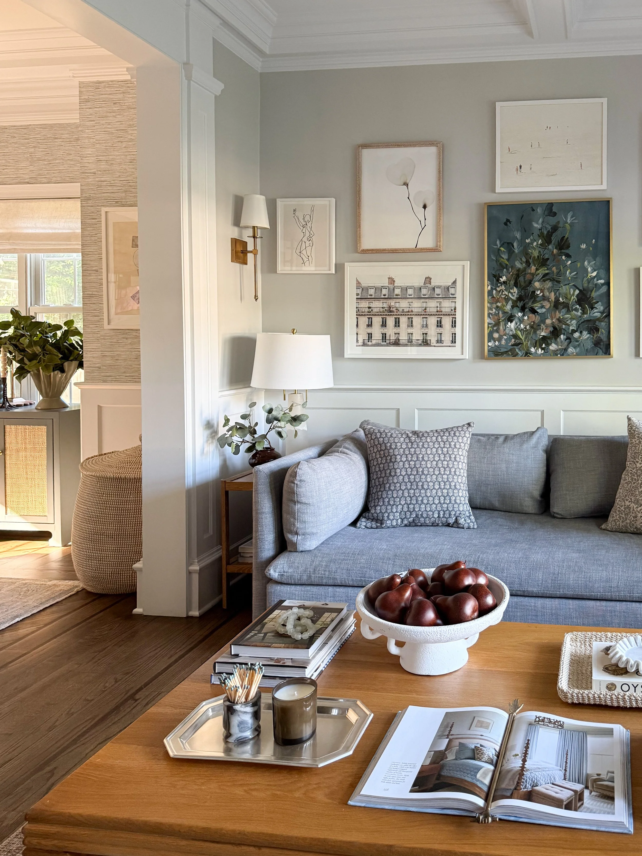 Finished living room design showcasing a gallery wall, neutral furnishings, layered lighting, decorative pillows, and a vintage inspired area rug.