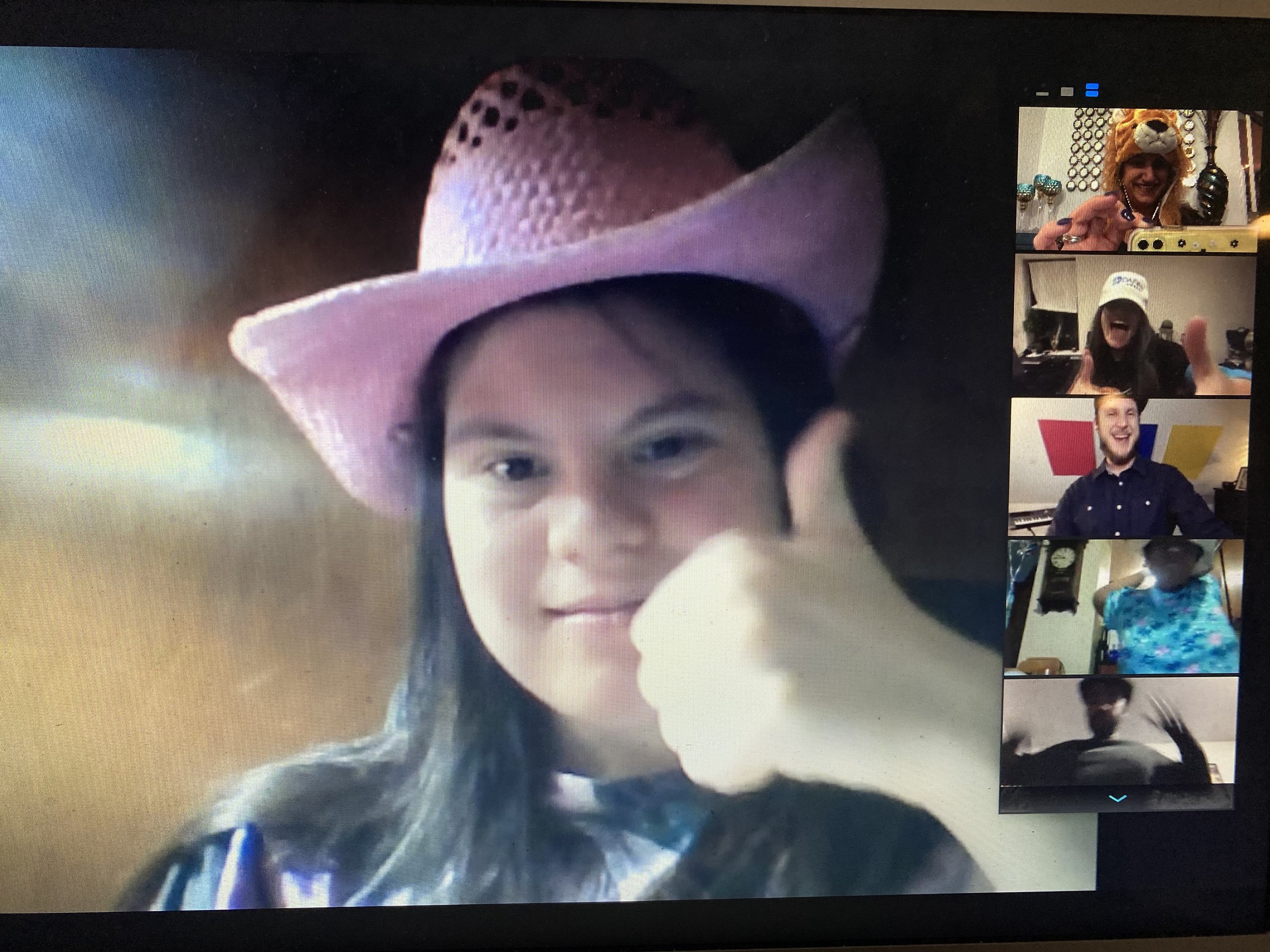  Image of a participant with long hair and a cowboy hat giving a thumbs up, during a virtual event on Zoom. 