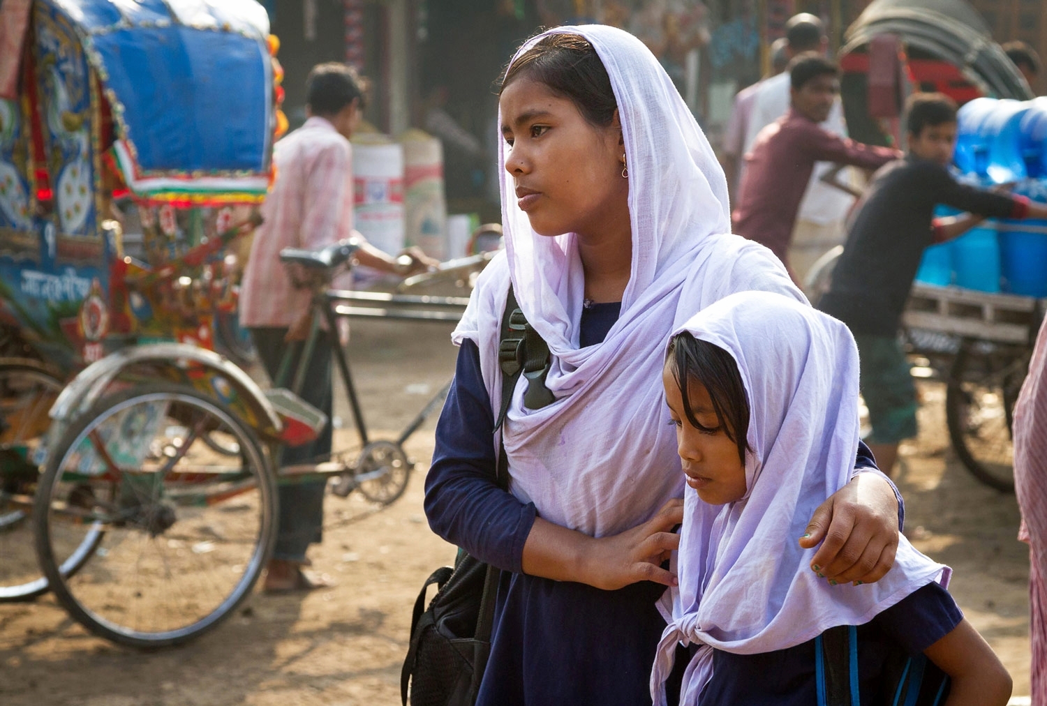 Two sisters await a rickshaw to take them to school; Duaripara slum, Dhaka, Bangladesh