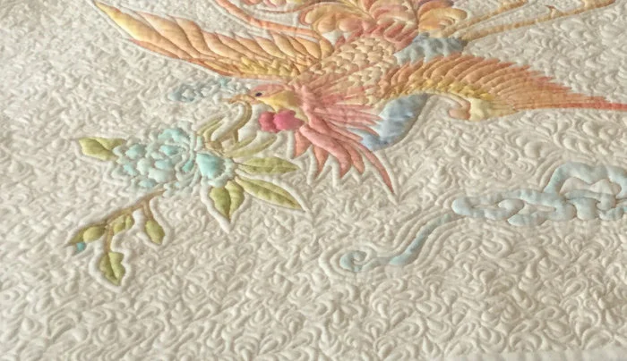 Golden Phoenix The piece is stitched on linen (front and back) with one layer of bonded cotton batting topped with two layers of wool (Hobbs Tuscany) batting. All of the background stitching is done with InvisaFil in several shades of gold. I just love how this thread adds subtle shading while it lets the quilting be the star! The outline of the Phoenix is done in a variety of threads, mostly PolyFast. Colour was added to the piece (watercolor pencils set with textile medium) after the completion of the quilting.