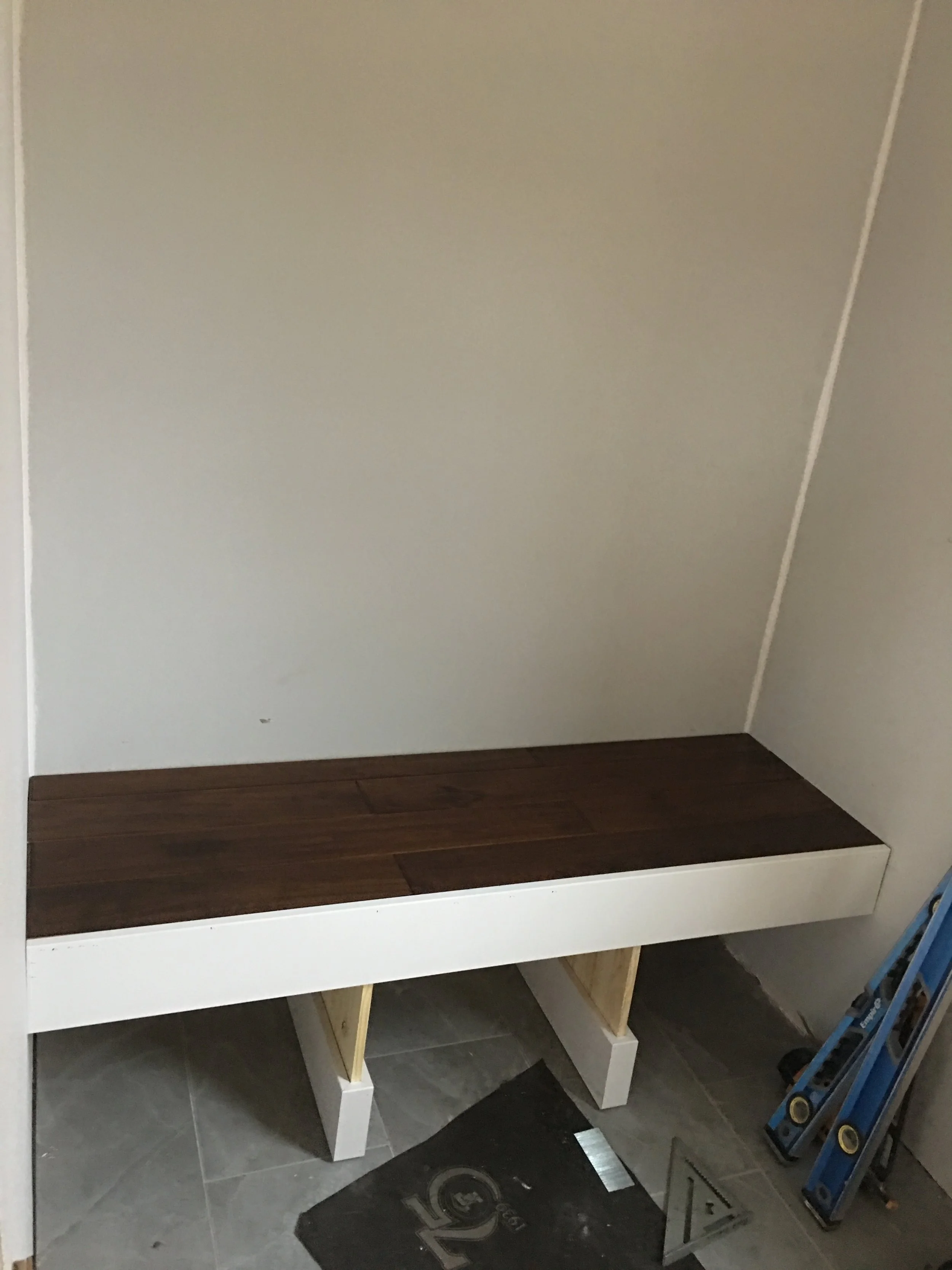 Beginning of custom built mudroom bench. tile flooring and hardwood.