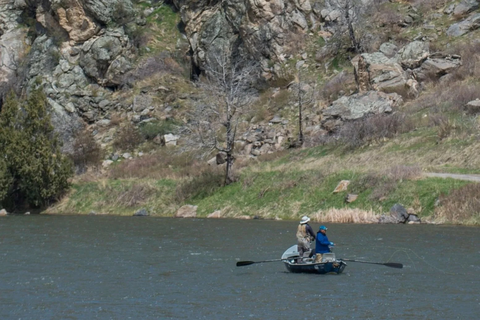Drift boat fly fishing below canyon walls on the Madison River, Montana