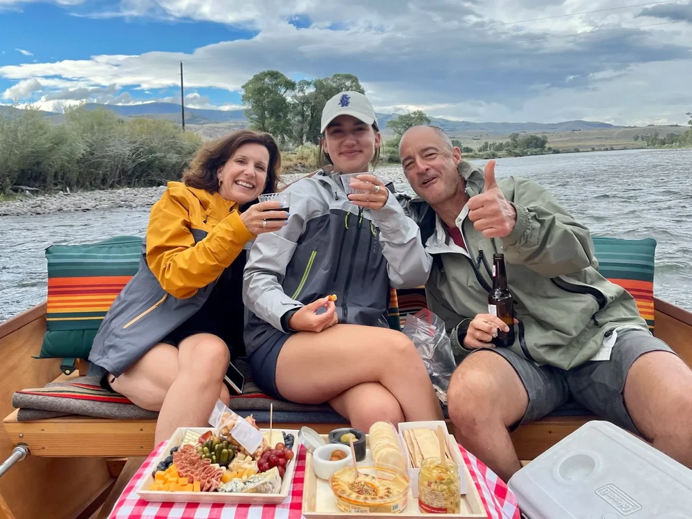 Guests relaxing in a wooden dory during a private scenic float on the Yellowstone River in Montana.