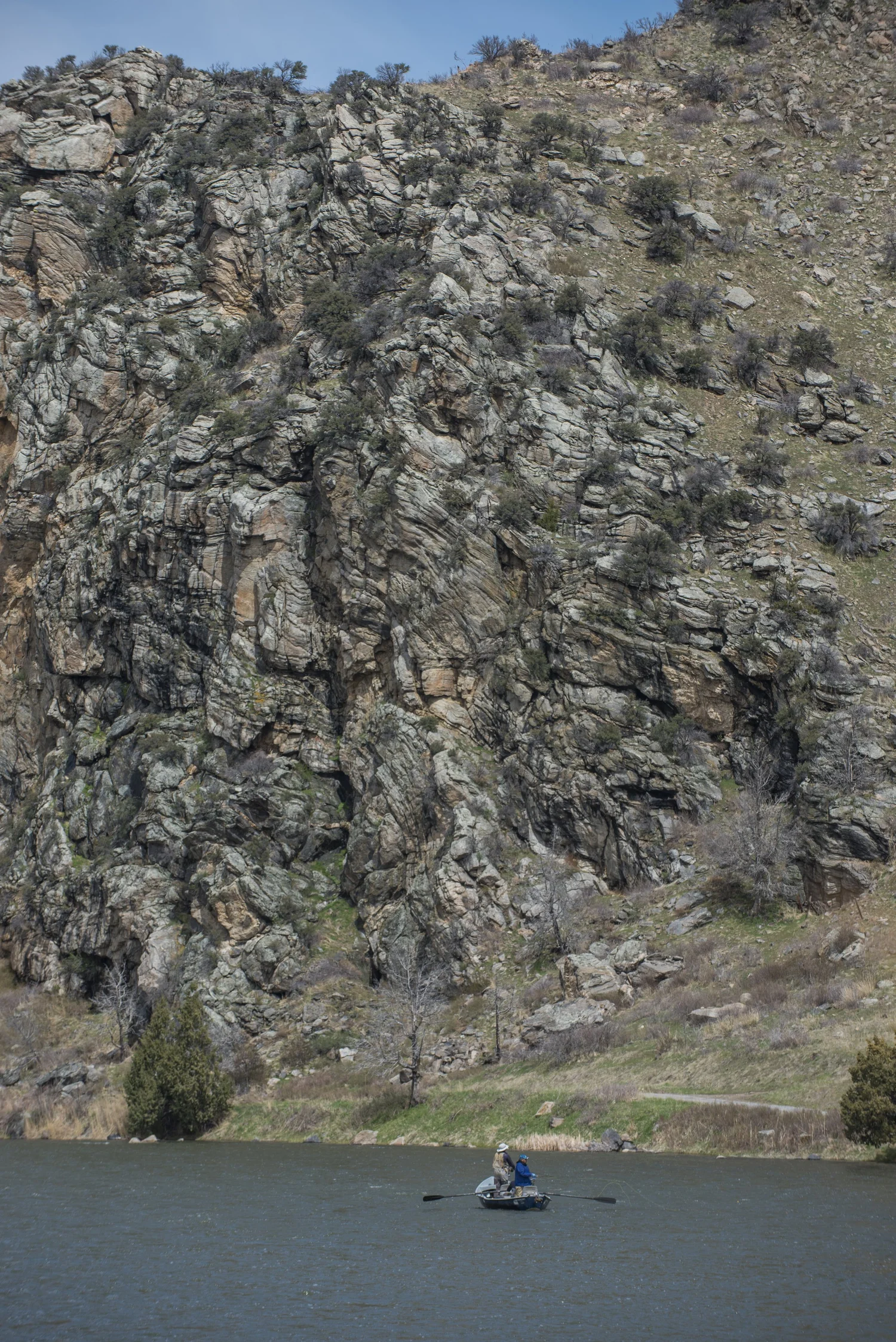 Drift boat fishing the Madison River in Montana with anglers working a long riffle.