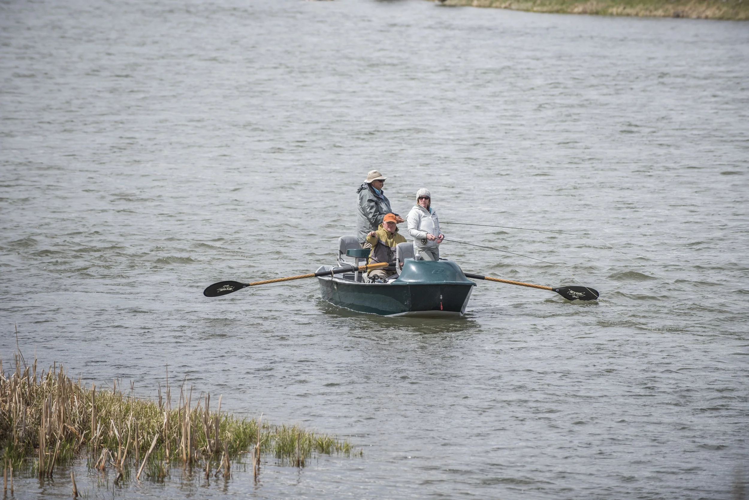 Winter fly fishing on the Lower Madison River in Bear Trap Canyon, with anglers in a drift boat below Ennis Lake near Livingston, Montana.