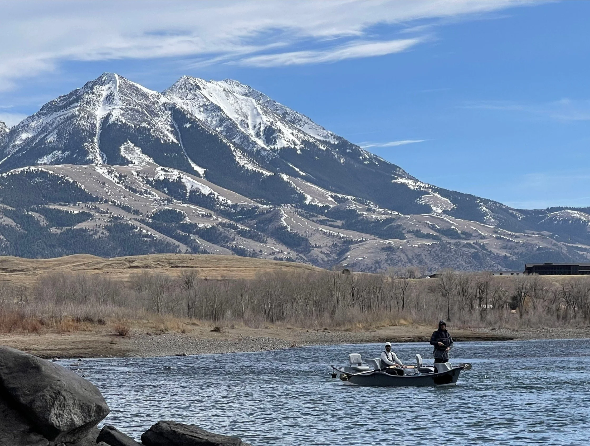 Drift boat fly fishing on the Yellowstone River in early spring with snow-covered mountains in Montana