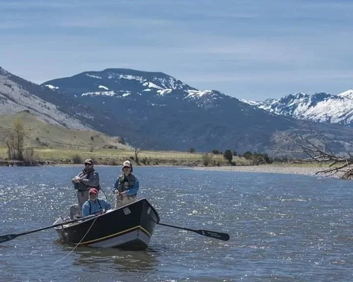 Three anglers in a drift boat on the Yellowstone River in Paradise Valley with snow on the Absaroka Mountains near Livingston, Montana