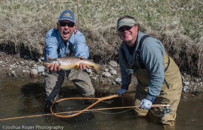 Anglers holding a brown trout during Montana Trout Camp in Montana.